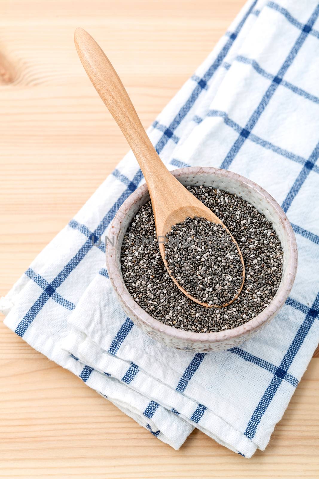 Nutritious chia seeds in ceramic bowl with wooden spoon for diet food ingredients.