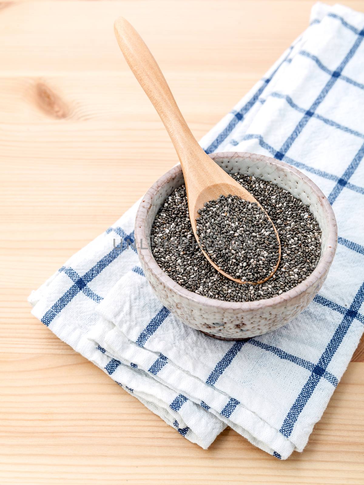 Nutritious chia seeds in ceramic bowl with wooden spoon for diet food ingredients.