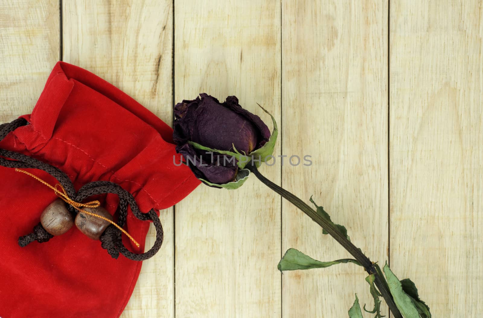 Dry roses with red small bag on wood pattern background