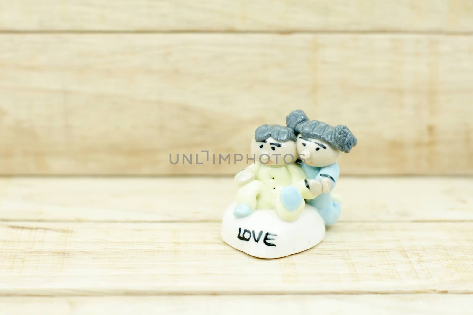 Little boy and girl ceramic dolls on wood pattern background