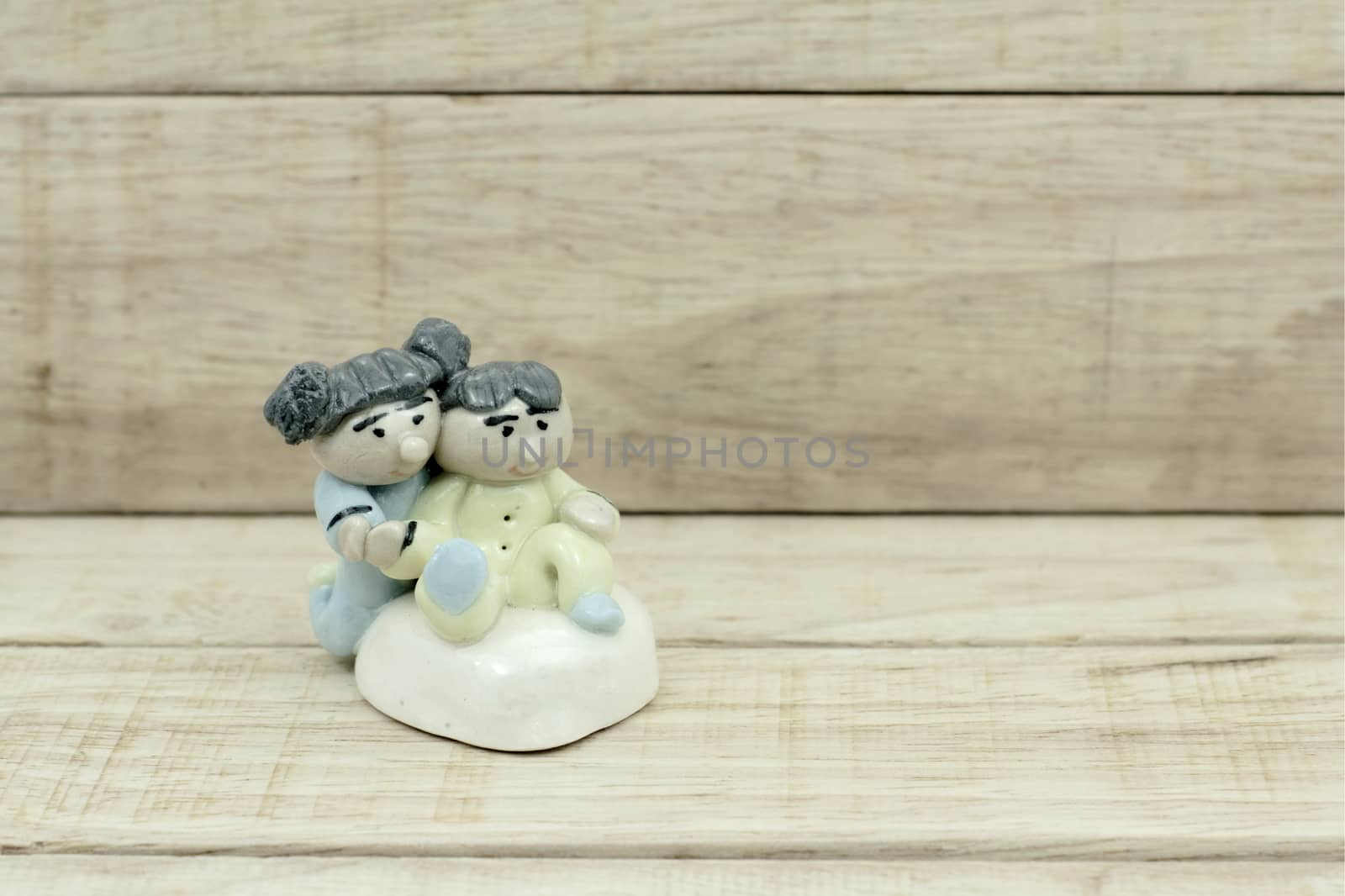 Little boy and girl ceramic dolls on wood pattern background