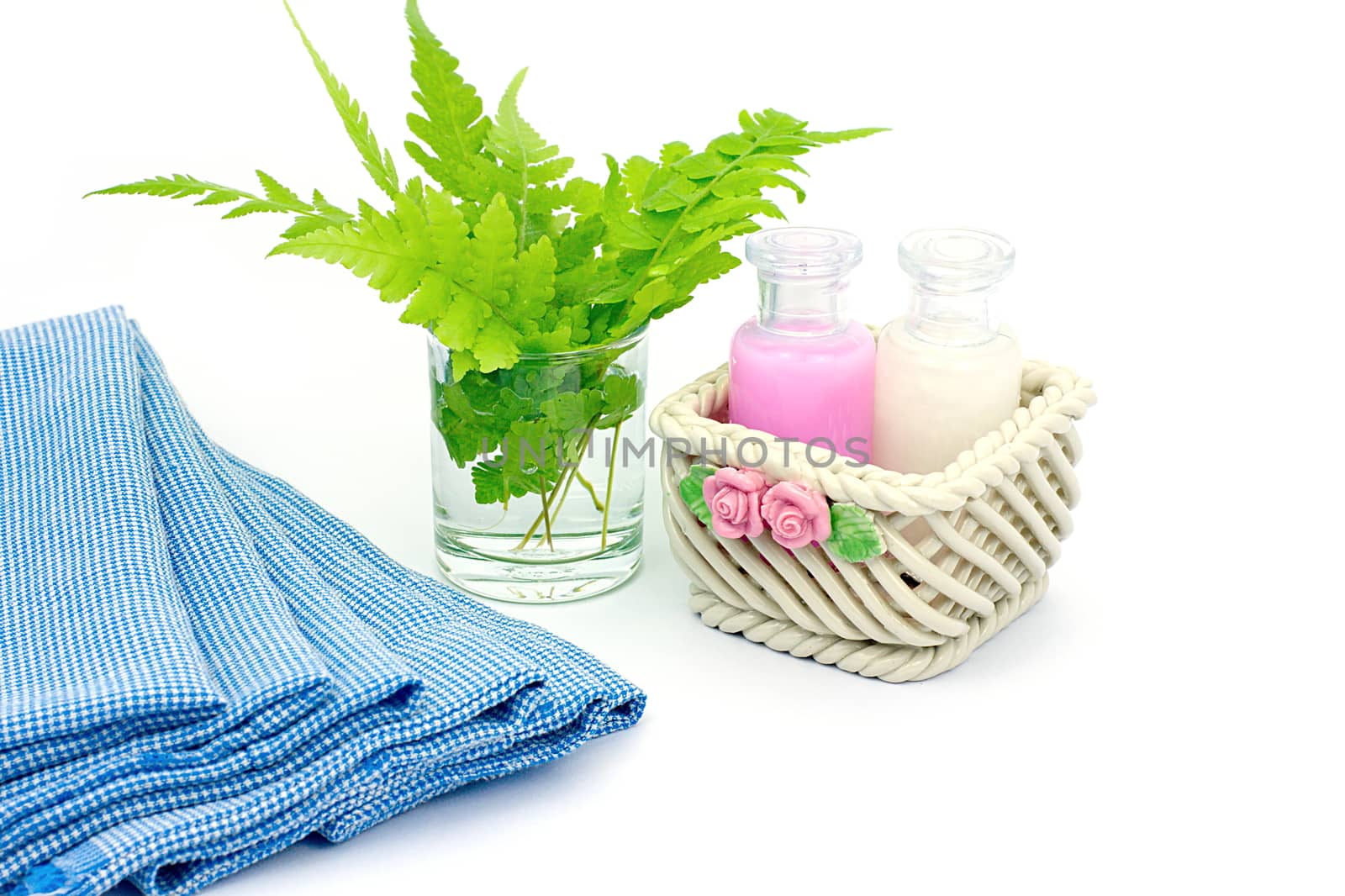 Shampoo and Shower gel put in ceramic basket on white background. Shampoo, Shower gel bottles with blue cloth and green leaves in a glass of water.