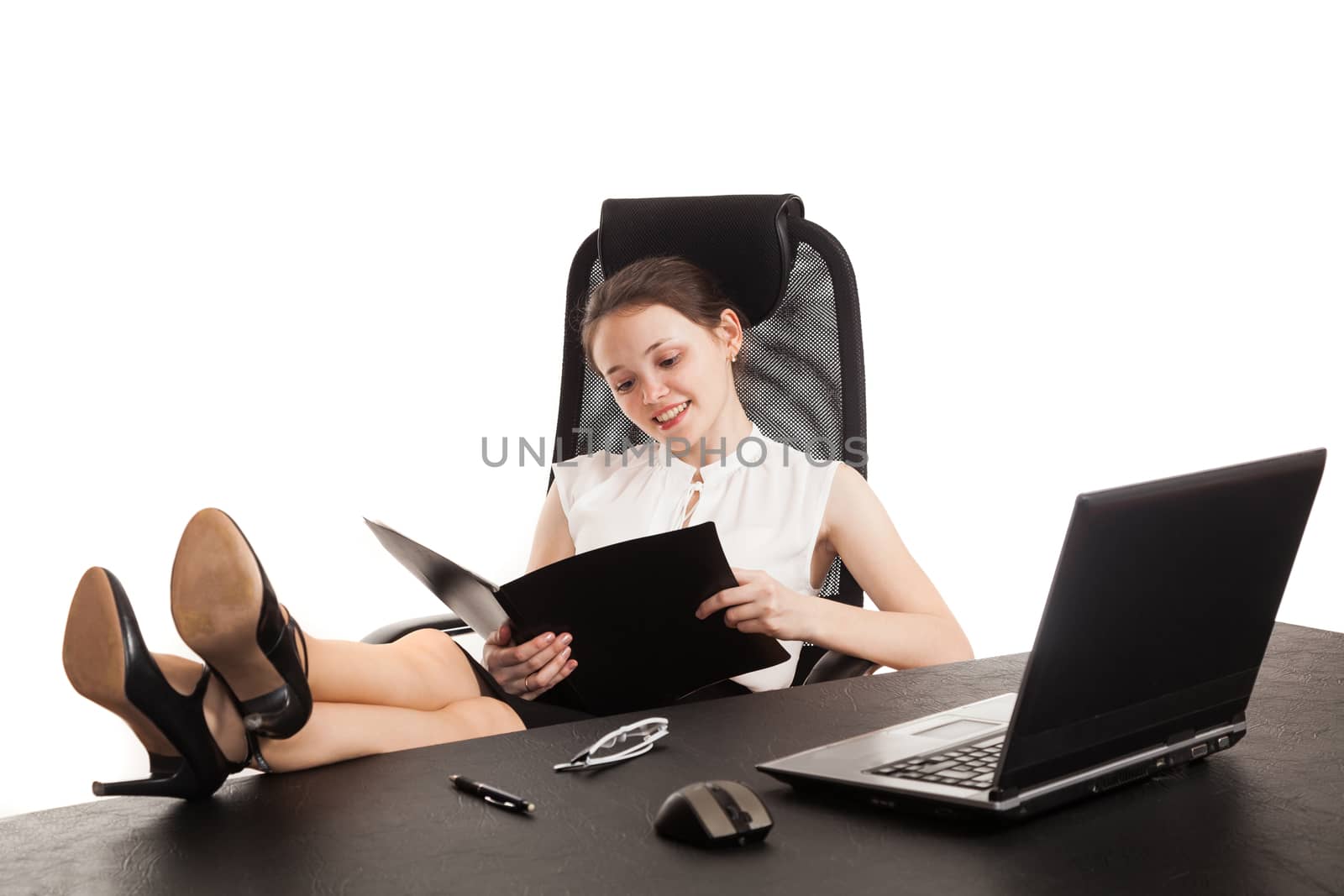 the business woman sits at office table with the laptop and reads the document