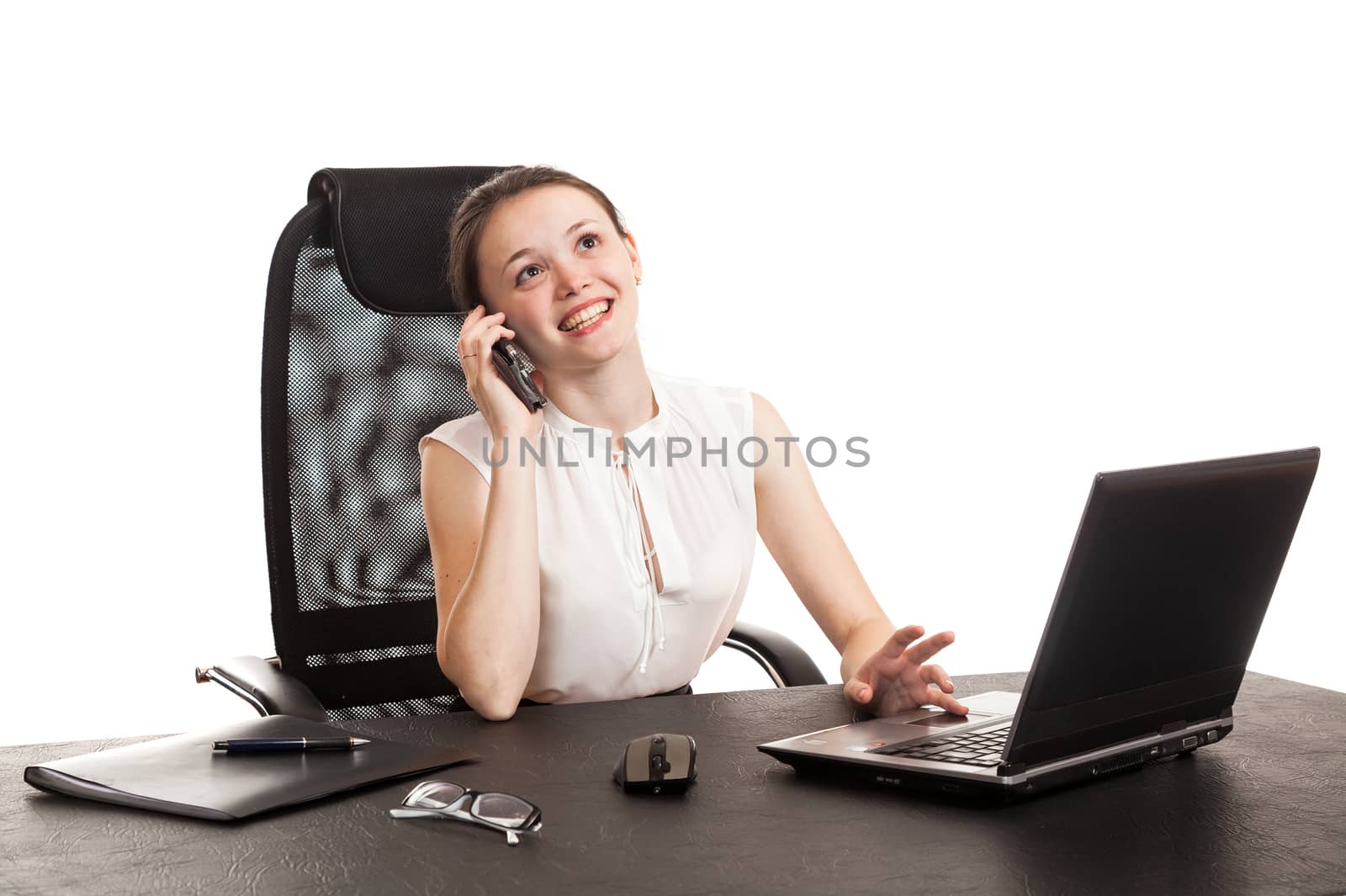 the business woman sits at office table with the laptop and speaks by phone