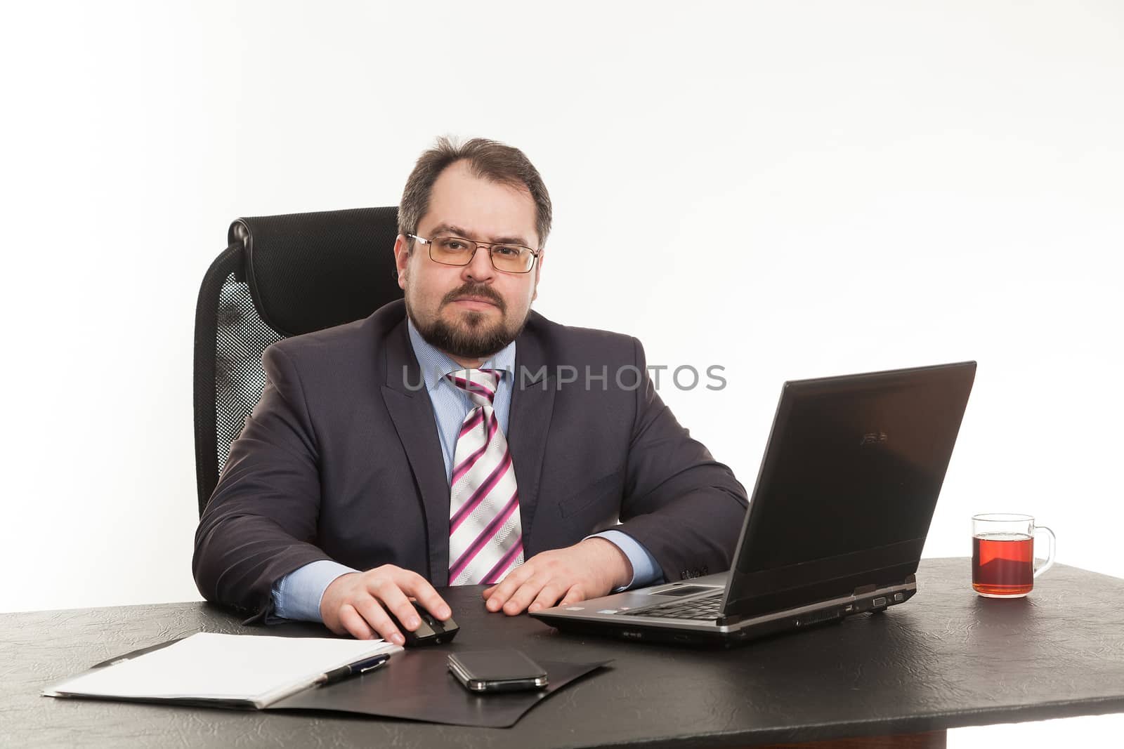 the businessman sits at office table with the laptop 