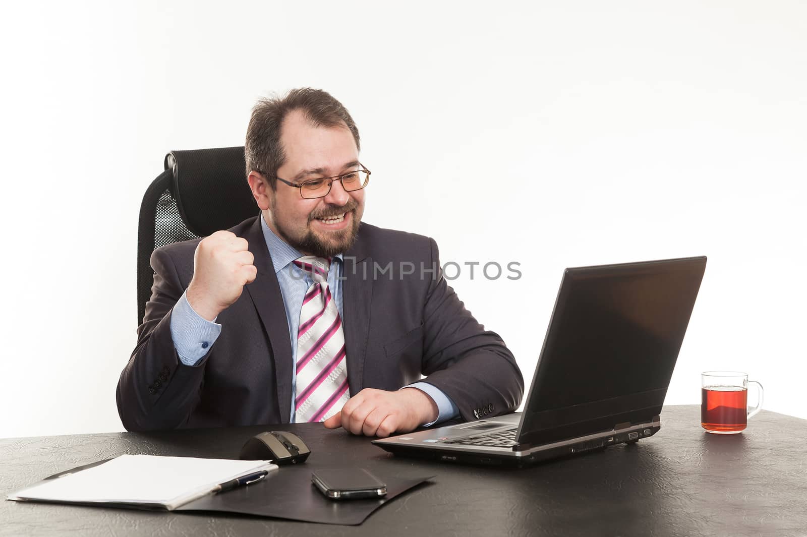 the businessman sits at office table with the laptop