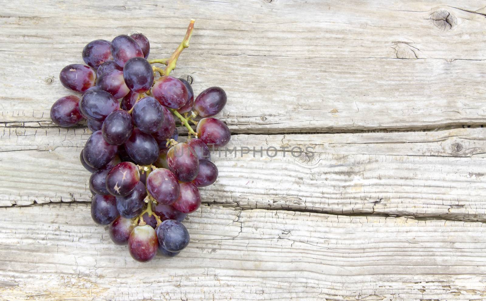 grapes on old wooden background by miradrozdowski
