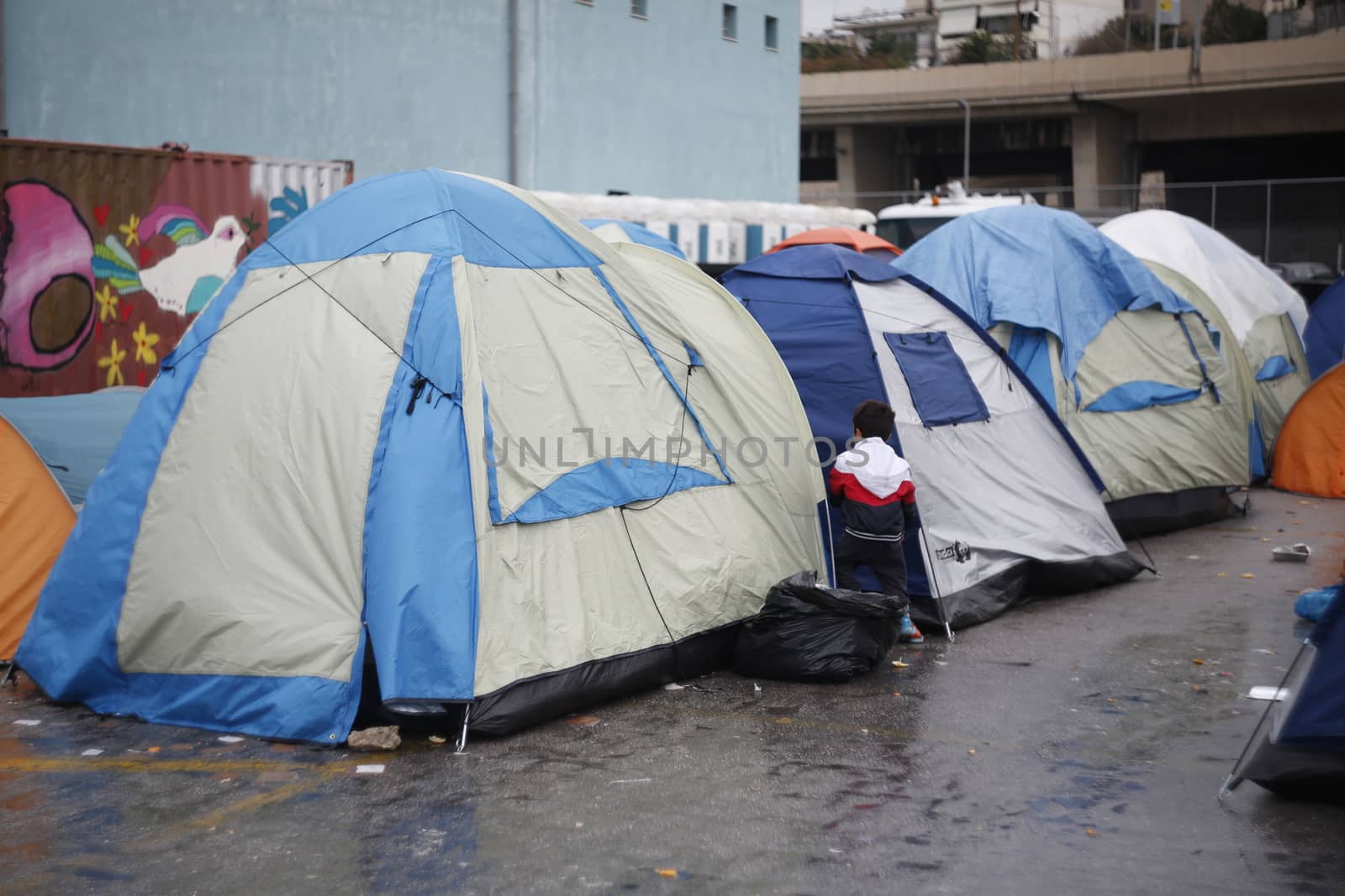 GREECE, Athens: Refugees continue to camp out under the rain, as thousands are still stranded at the Port of Piraeus in Athens, Greece on March 27, 2016. A deal between the European Union and Turkey has aimed to curb the influx of refugees to Greece, saying reception centers have become detention facilities. 