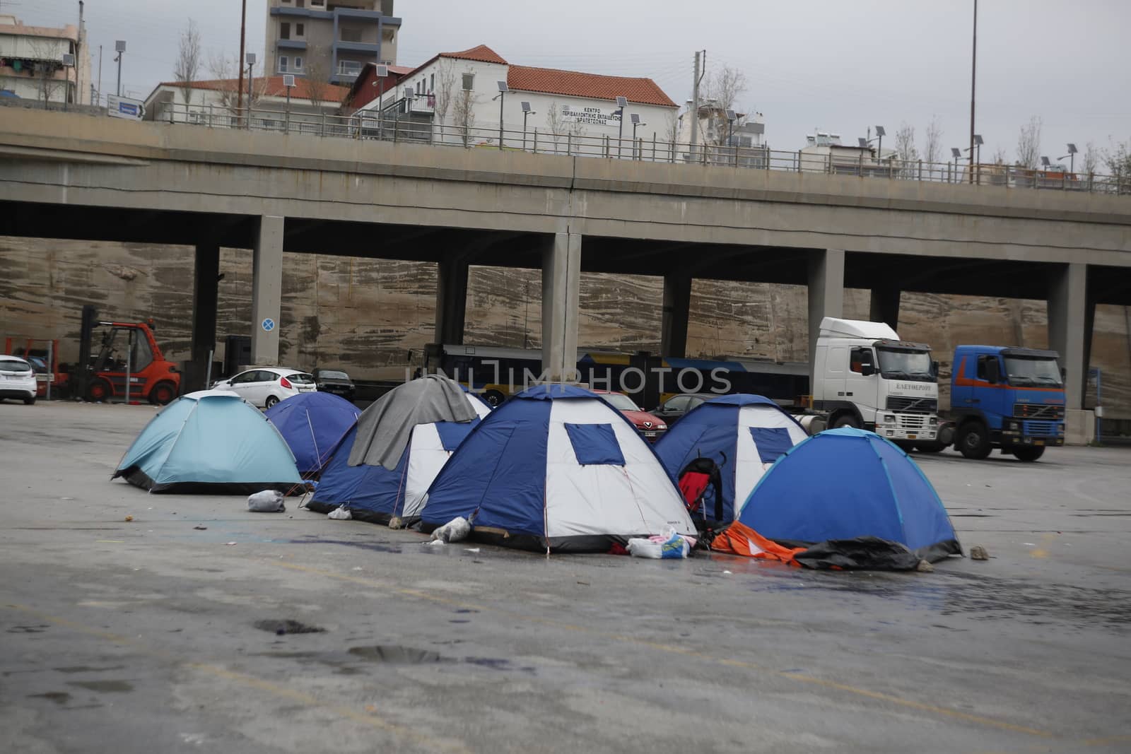 GREECE, Athens: Refugees continue to camp out under the rain, as thousands are still stranded at the Port of Piraeus in Athens, Greece on March 27, 2016. A deal between the European Union and Turkey has aimed to curb the influx of refugees to Greece, saying reception centers have become detention facilities. 