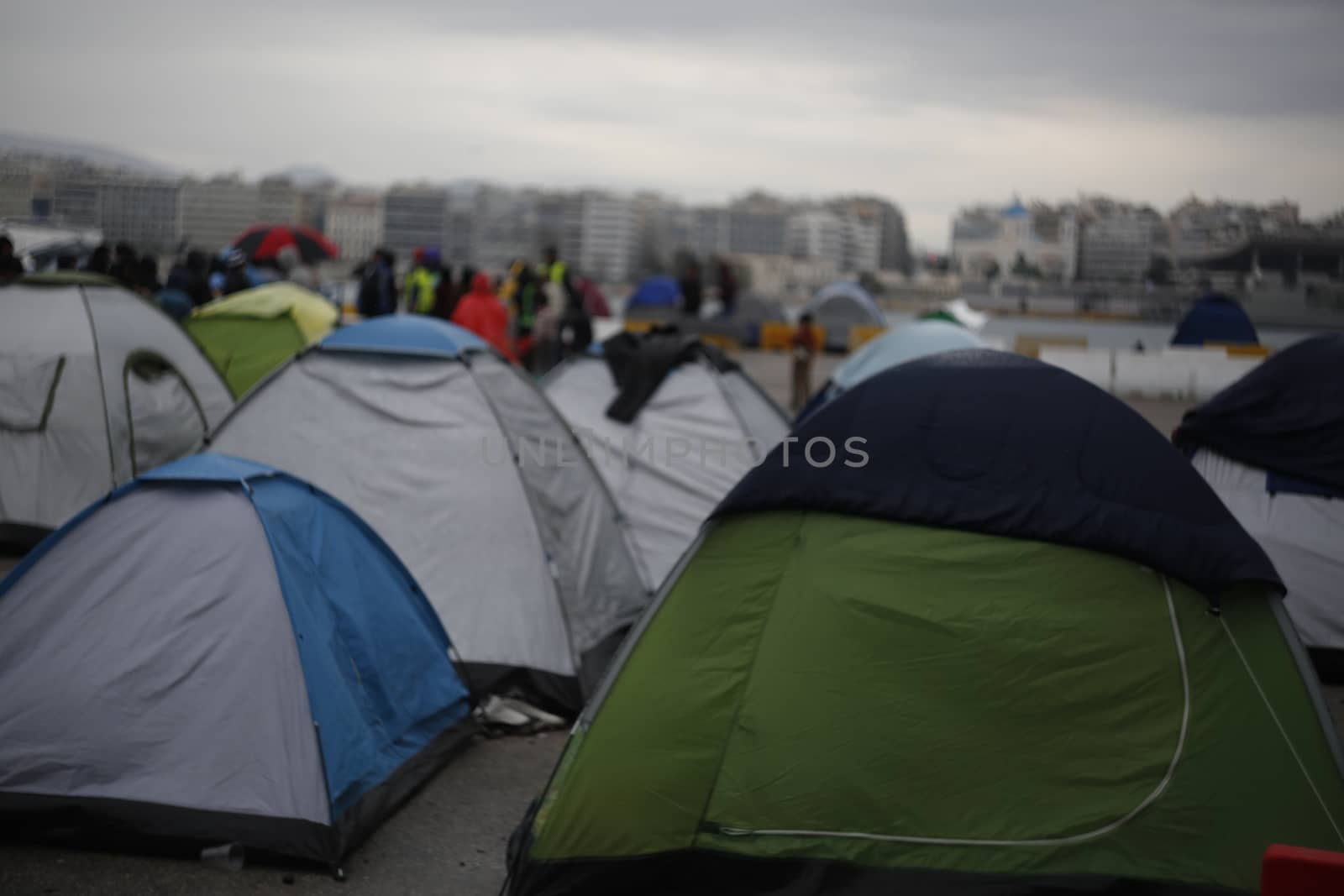 GREECE, Athens: Refugees continue to camp out under the rain, as thousands are still stranded at the Port of Piraeus in Athens, Greece on March 27, 2016. A deal between the European Union and Turkey has aimed to curb the influx of refugees to Greece, saying reception centers have become detention facilities. 
