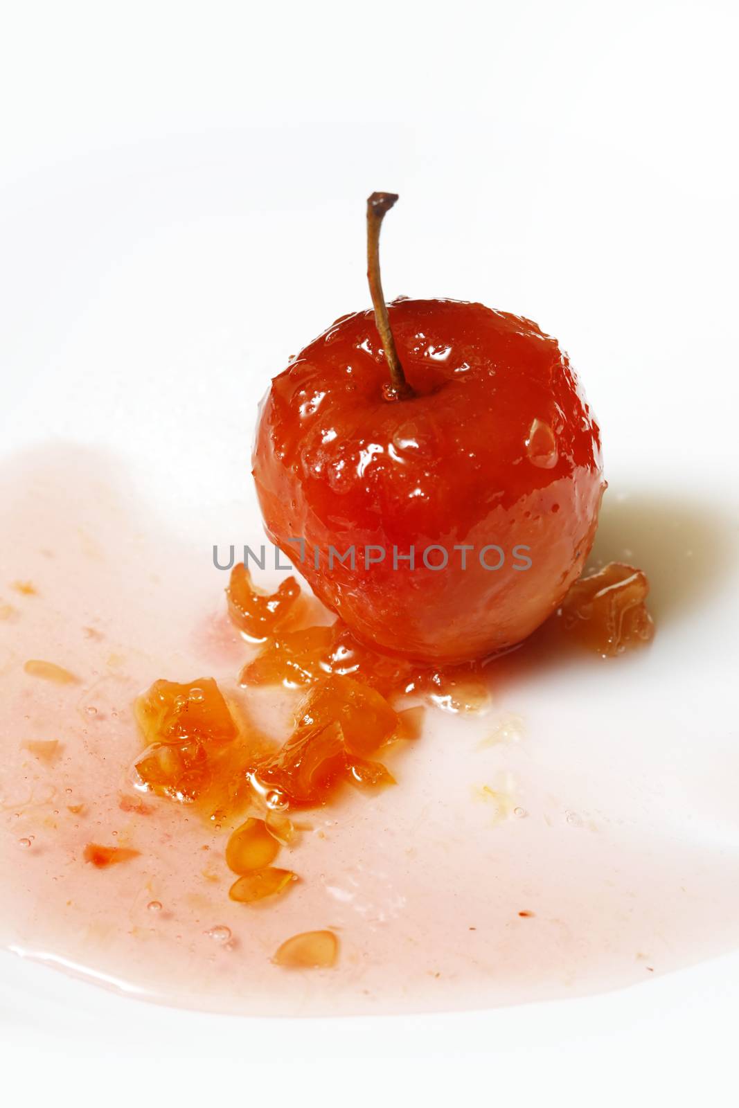 Red apple in rose syrup with small pieces of zucchini over isolated white background