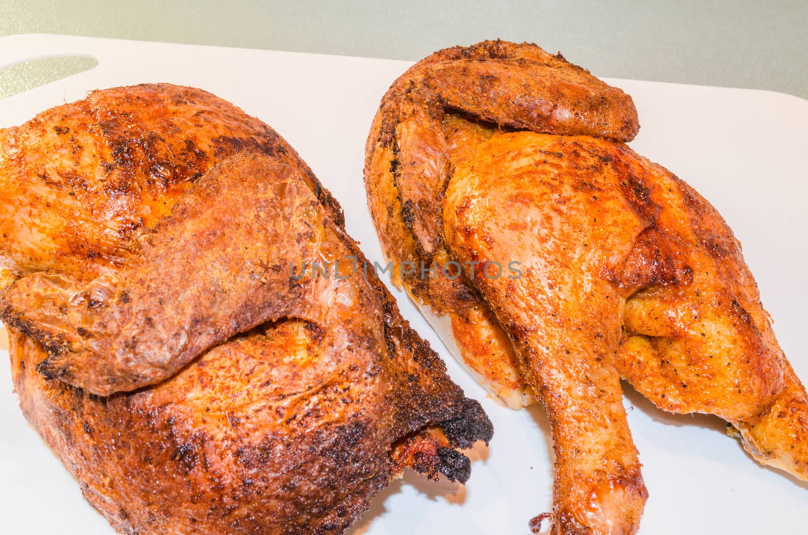 Beautiful brown grilled chicken legs on white plate.