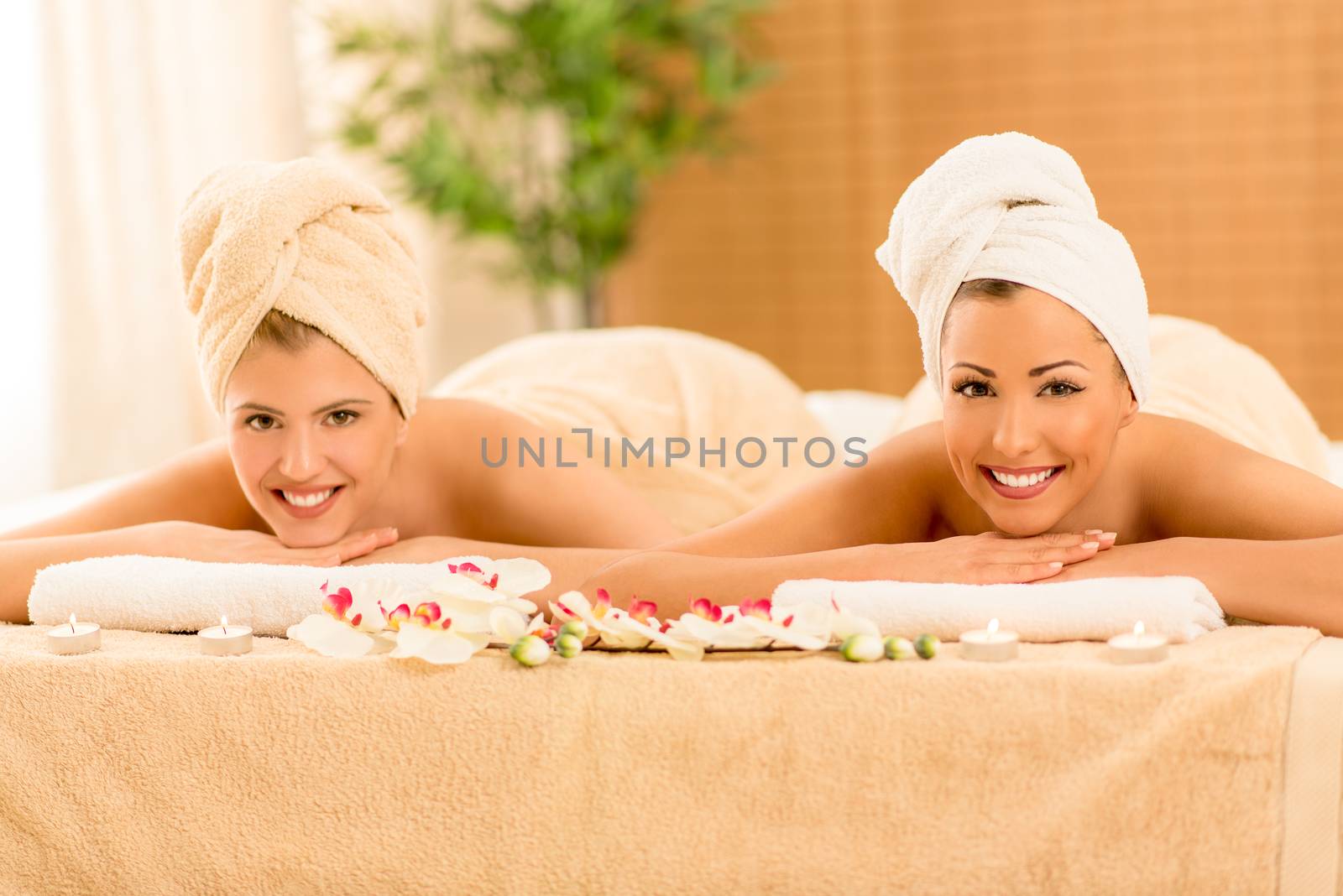 Two cute young women enjoying during a skin care treatment at a spa. Looking at camera.