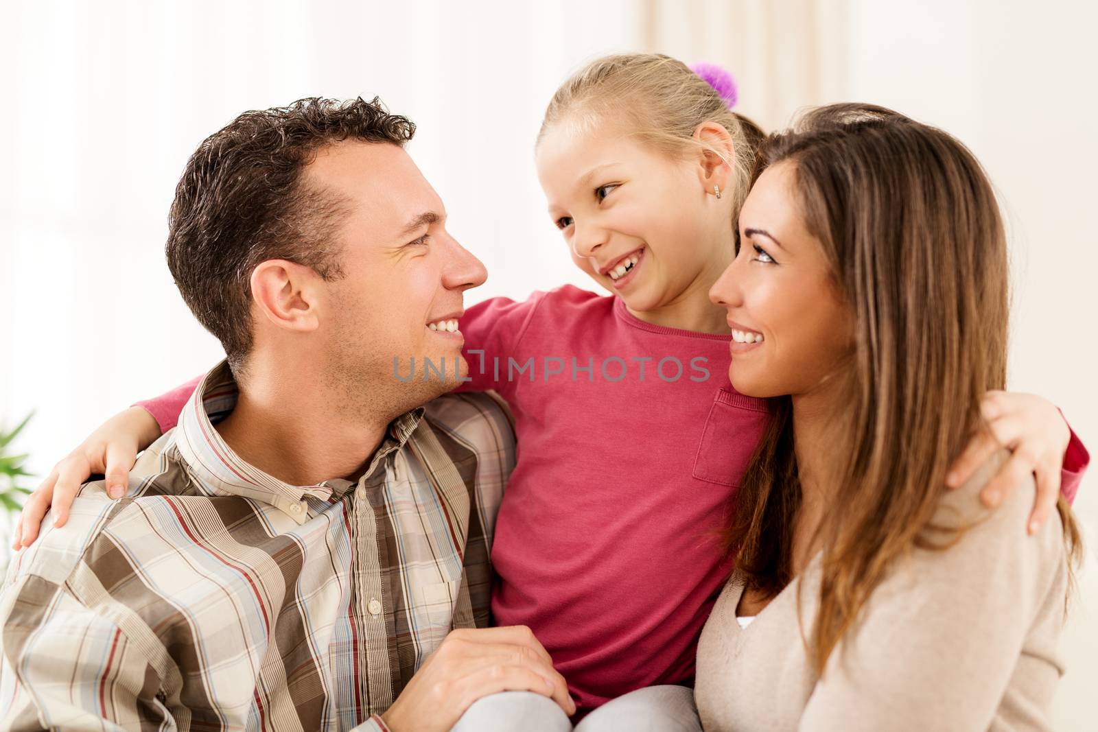 Beautiful young smiling family relaxing on sofa at living room.