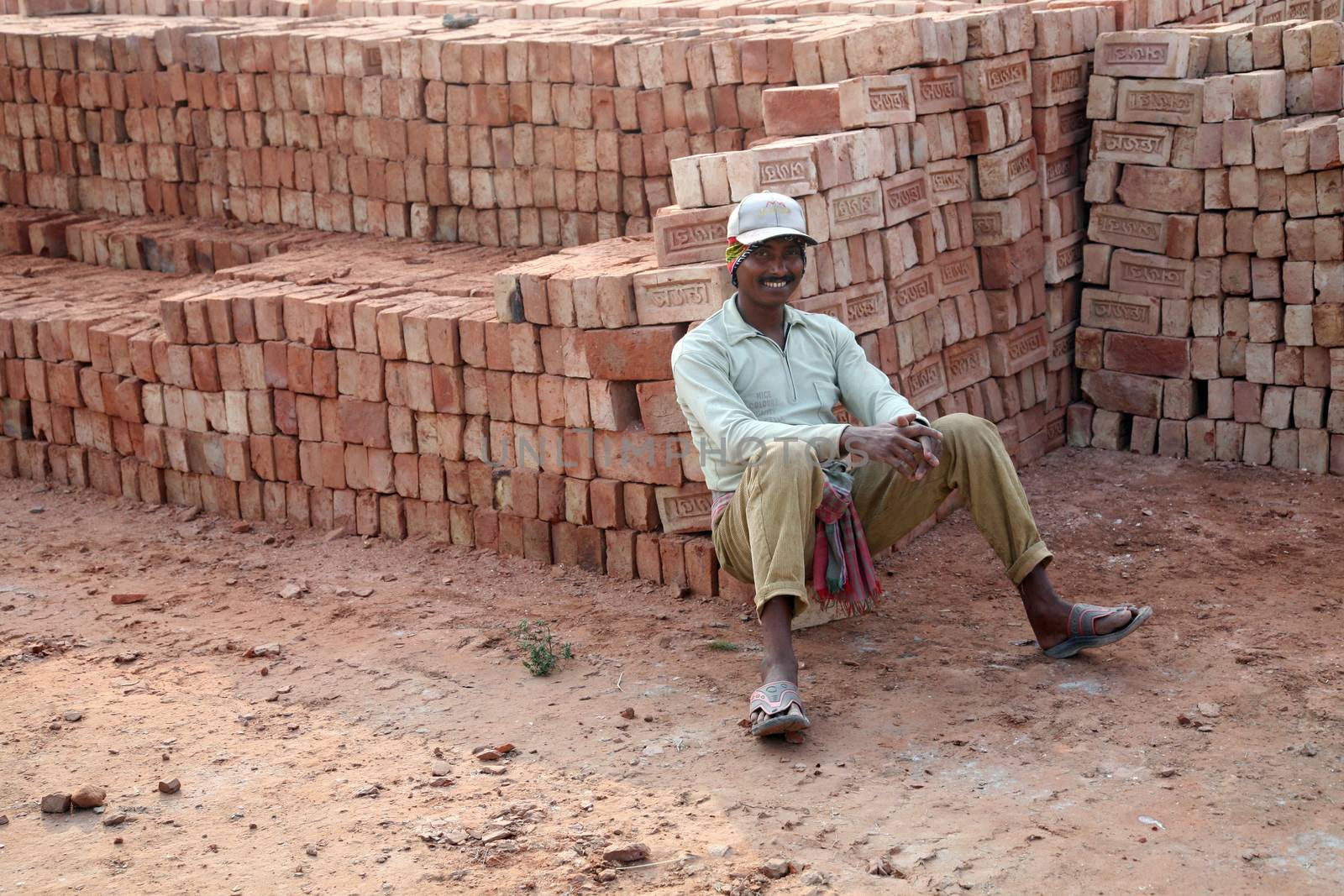 Brick field workers rest after hard work, wearing just baked brick from the kiln in truck in Sarberia, West Bengal, India.