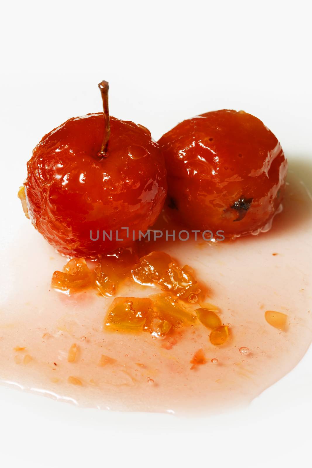 Red apples in rose syrup with small pieces of zucchini over isolated white background