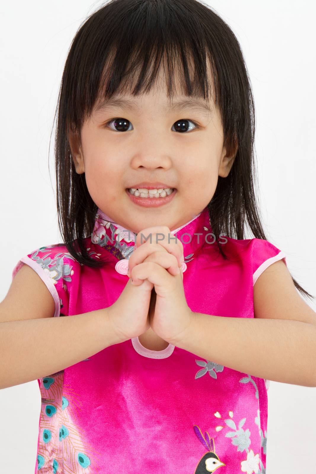 Chinese Little Girl wearing Cheongsam with greeting gesture in plain white background.