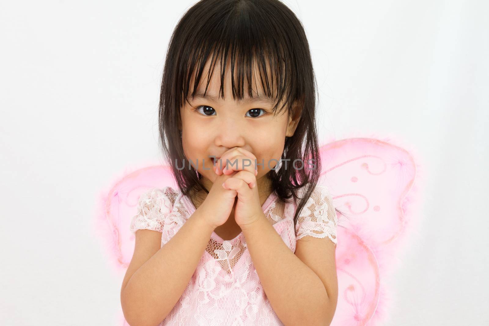 Chinese little girl wearing butterfly custome with praying gesture in plain white background