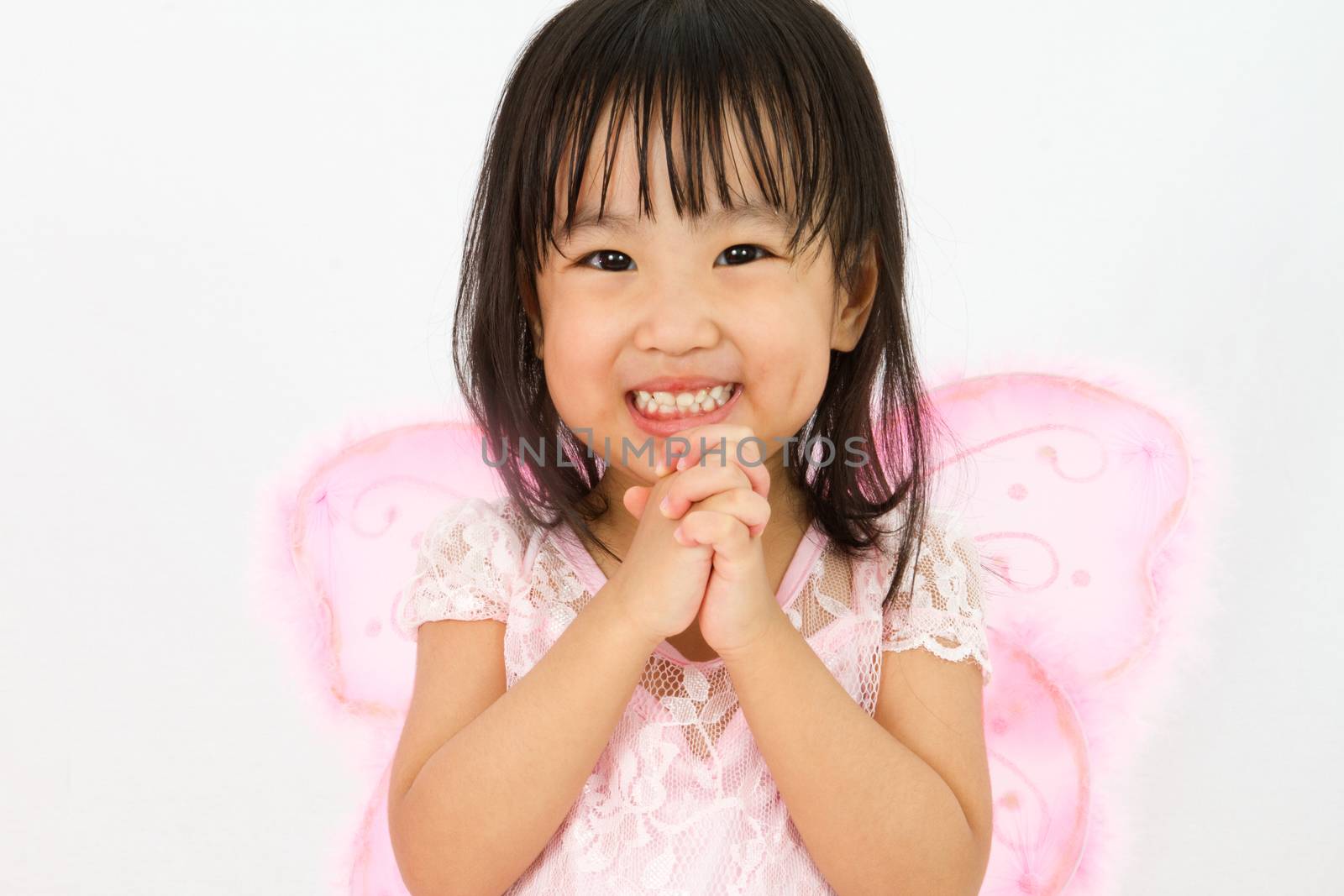 Chinese little girl wearing butterfly custome with praying gesture in plain white background