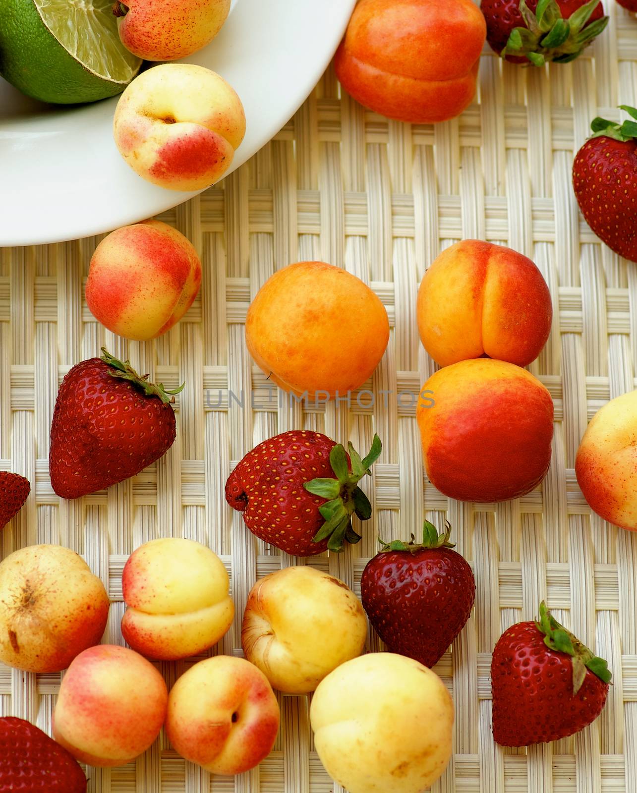 Arrangement of Various Summer Fruits with Ripe Apricots, Strawberries, Peaches, Nectarines and Lime closeup on Wicker background. Top View