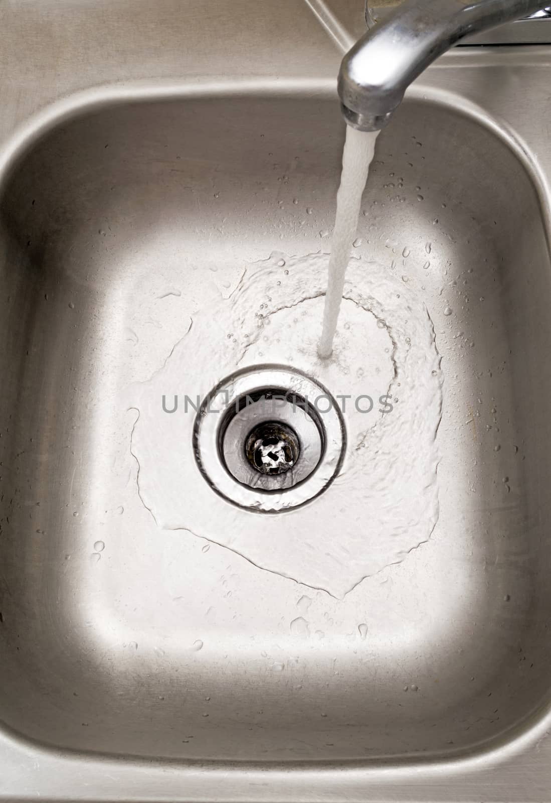 Close up shot of a stainless steel sink with water running down the drain.