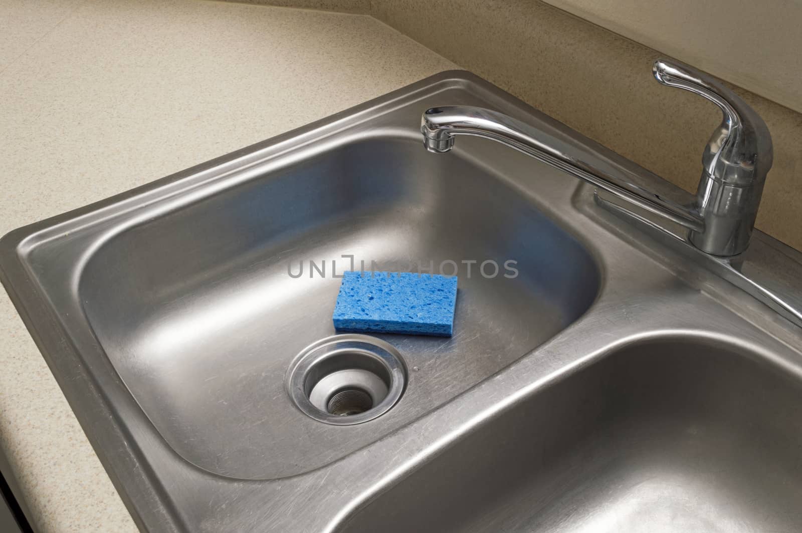 Empty stainless steel sink with blue sponge.
