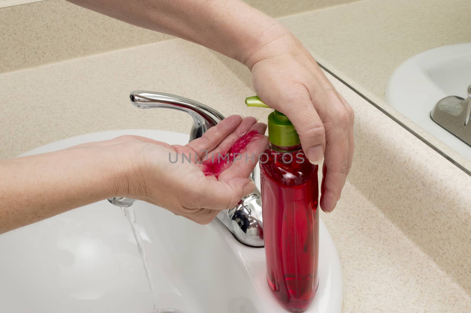 Female hand pressing liquid soap into hand to clean hands.
