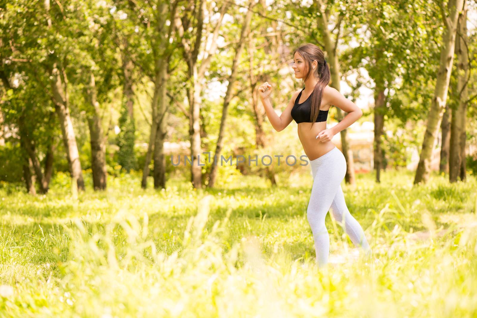 Happy young beautiful woman running in the park