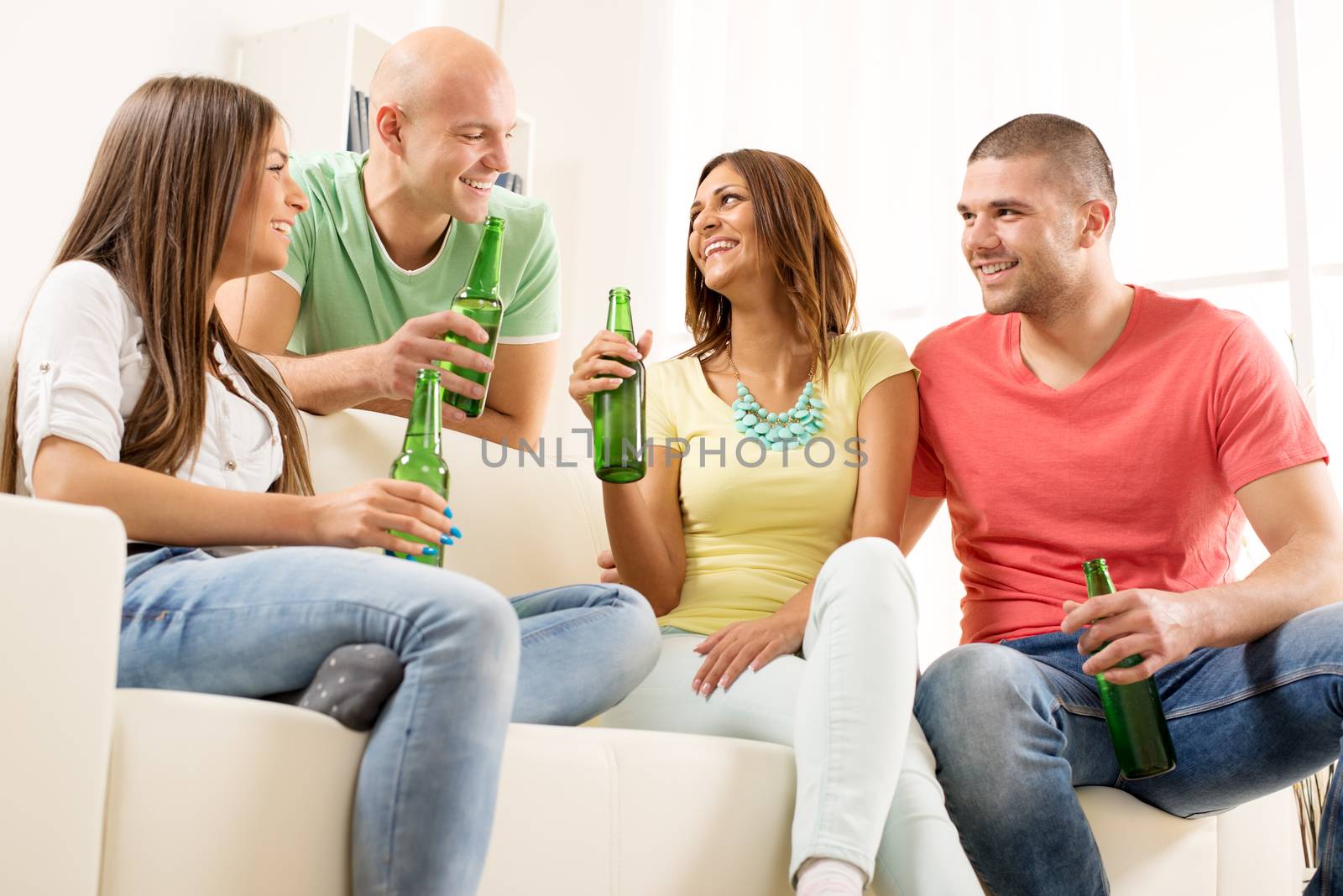 Four friends enjoying with beer together at the home party.
