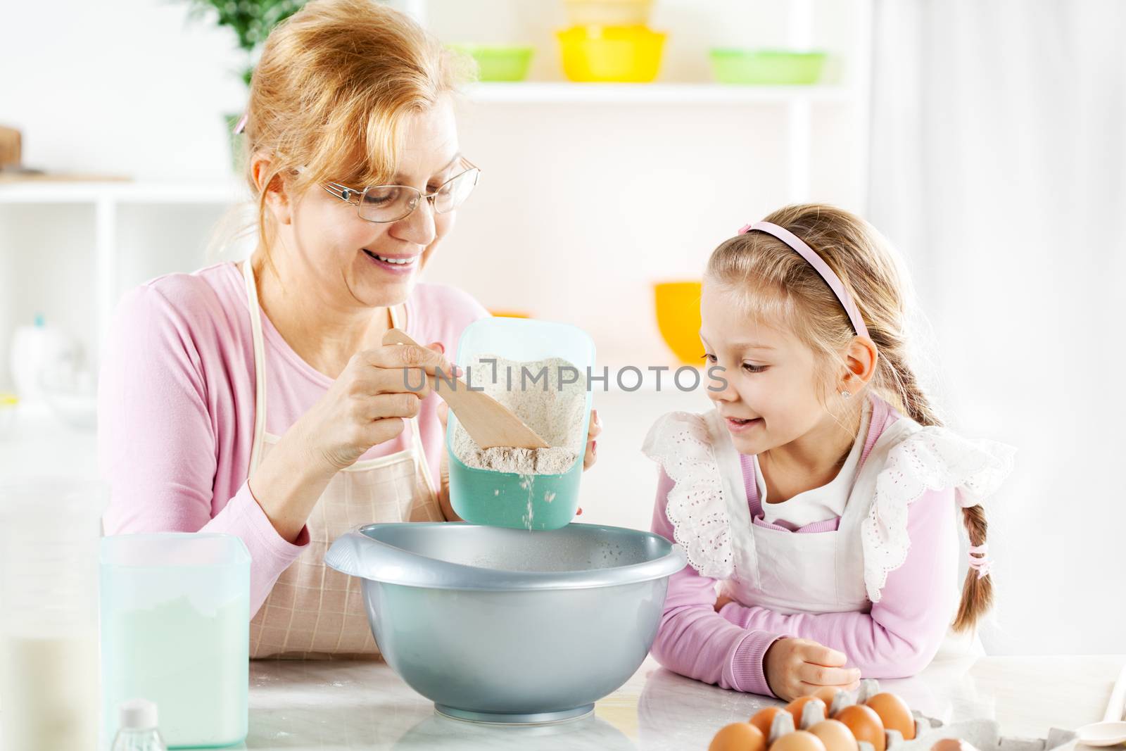 Beautiful happy grandmother learning her granddaughter Baking in a kitchen. 