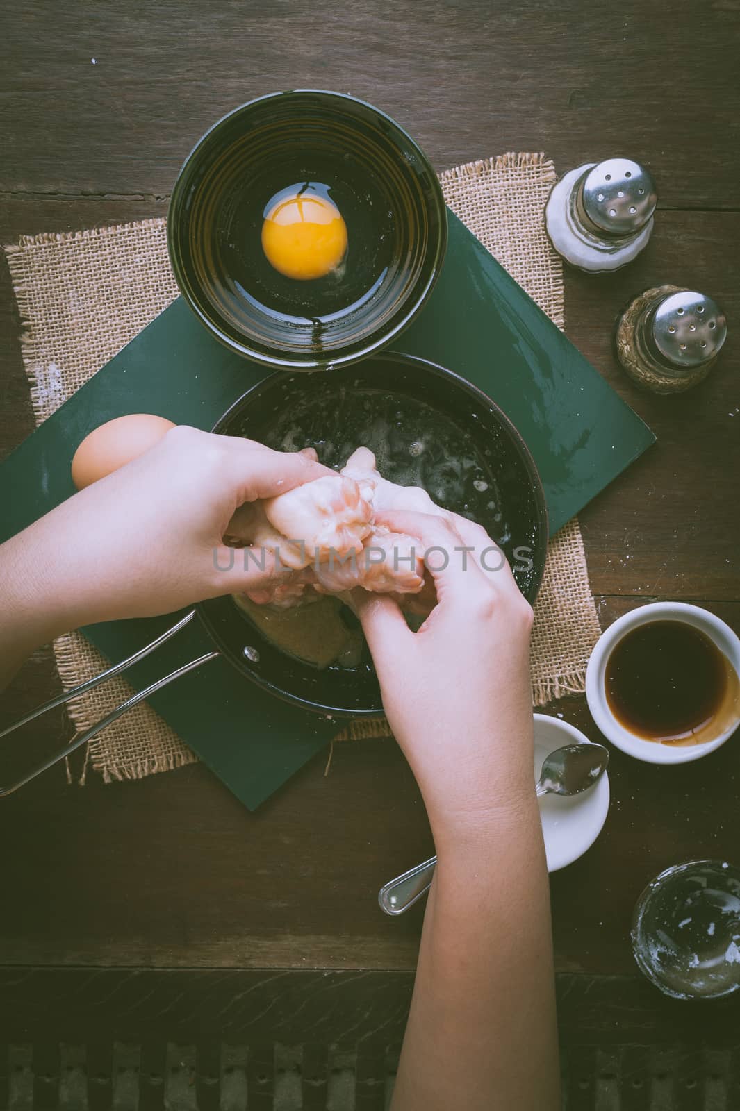 Preparation for cooking in home kitchen. Woman hand mixing ingredients with chicken wings with vintage filter effect.