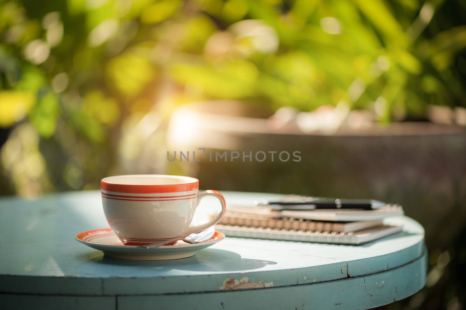 Coffee cup, notebooks, and pen on blue veteran table in morning time