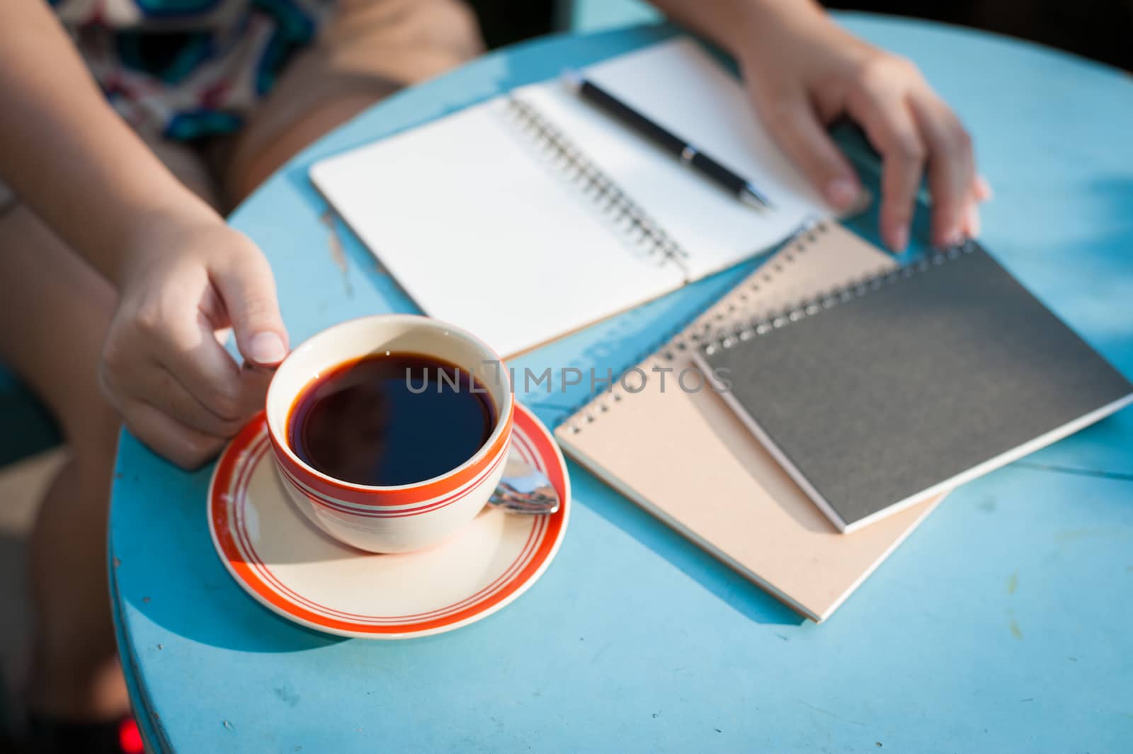 Woman right hand holding coffee cup during coffee break in cafe with morning scene