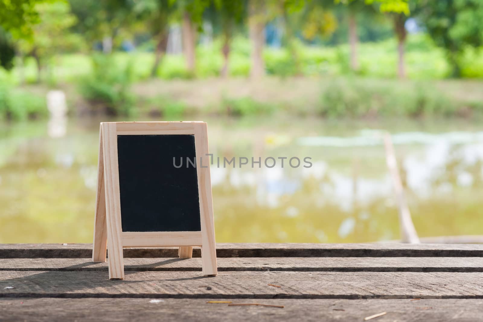 Small A-frame blackboard with blank area for text or message on rustic wood table in morning time