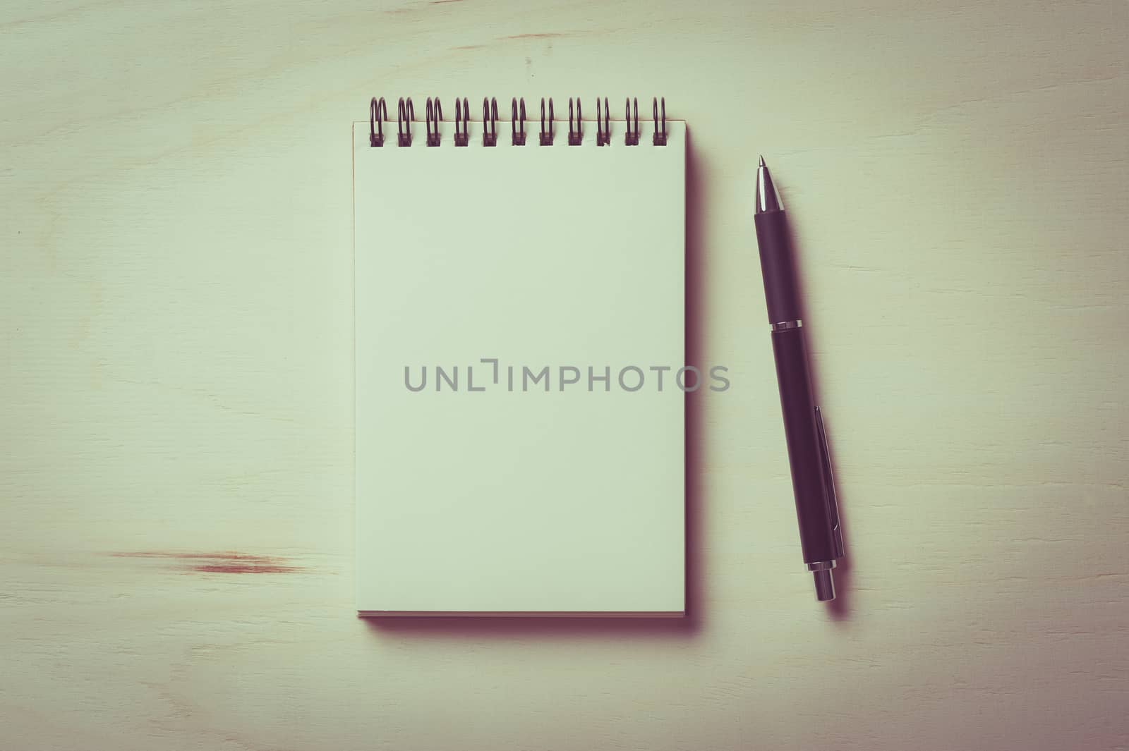 Opened notebook with blank area for text or message and pen on wood table with vintage filter effect