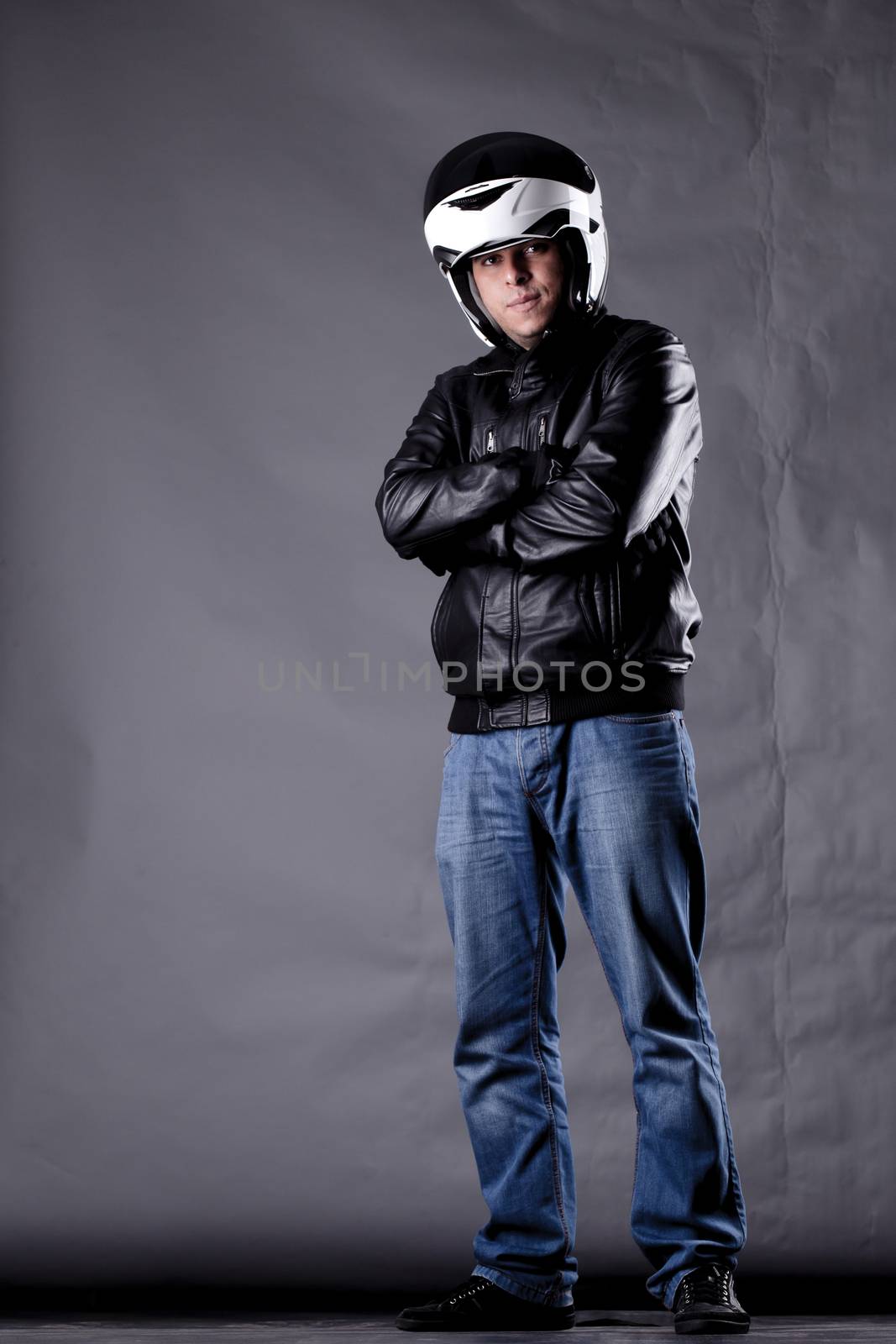 motorist with a helmet, leather jacket and jeans, on grunge background with harsh lighting