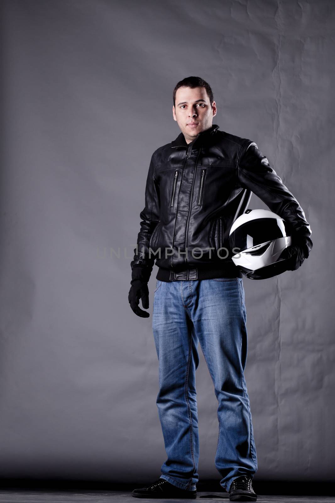 motorist with a helmet, leather jacket and jeans, on grunge background with harsh lighting