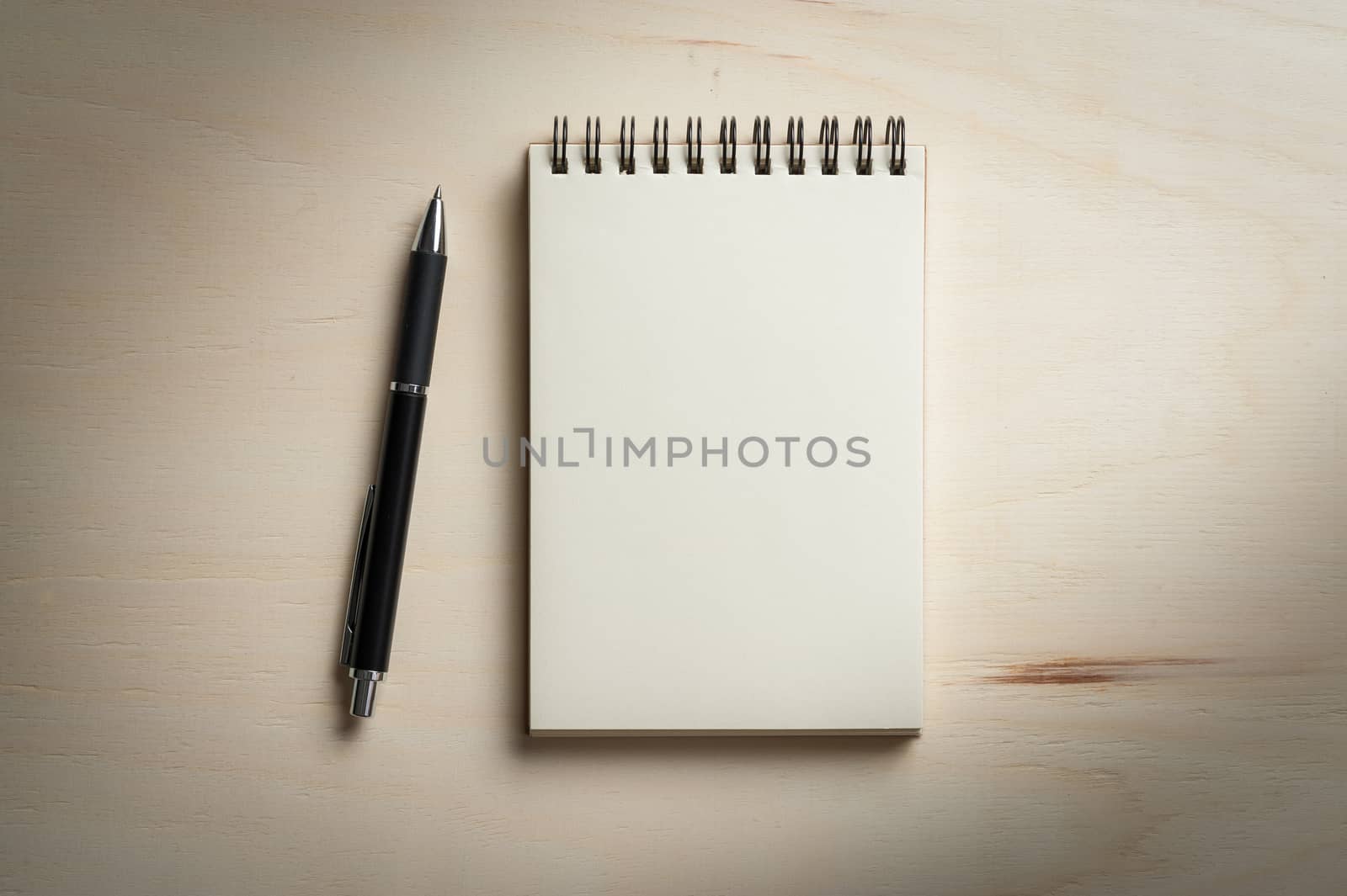 Opened notebook with blank area for text or message and pen on wood table with low key scene