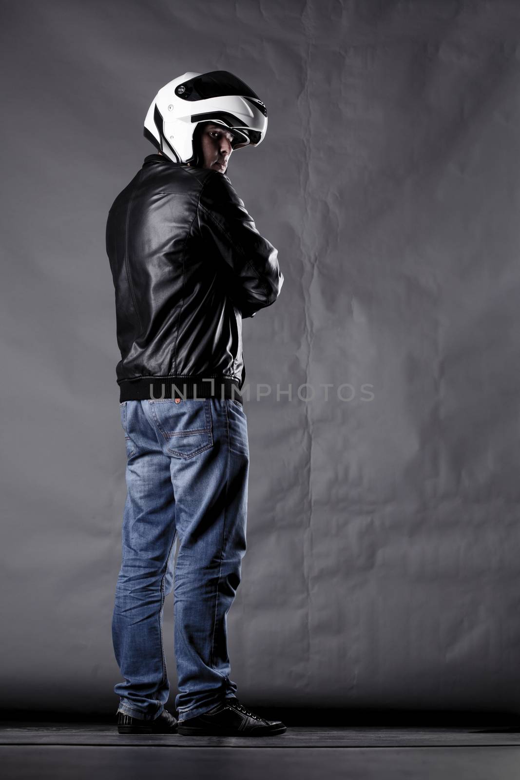 motorist with a helmet, leather jacket and jeans, on grunge background with harsh lighting