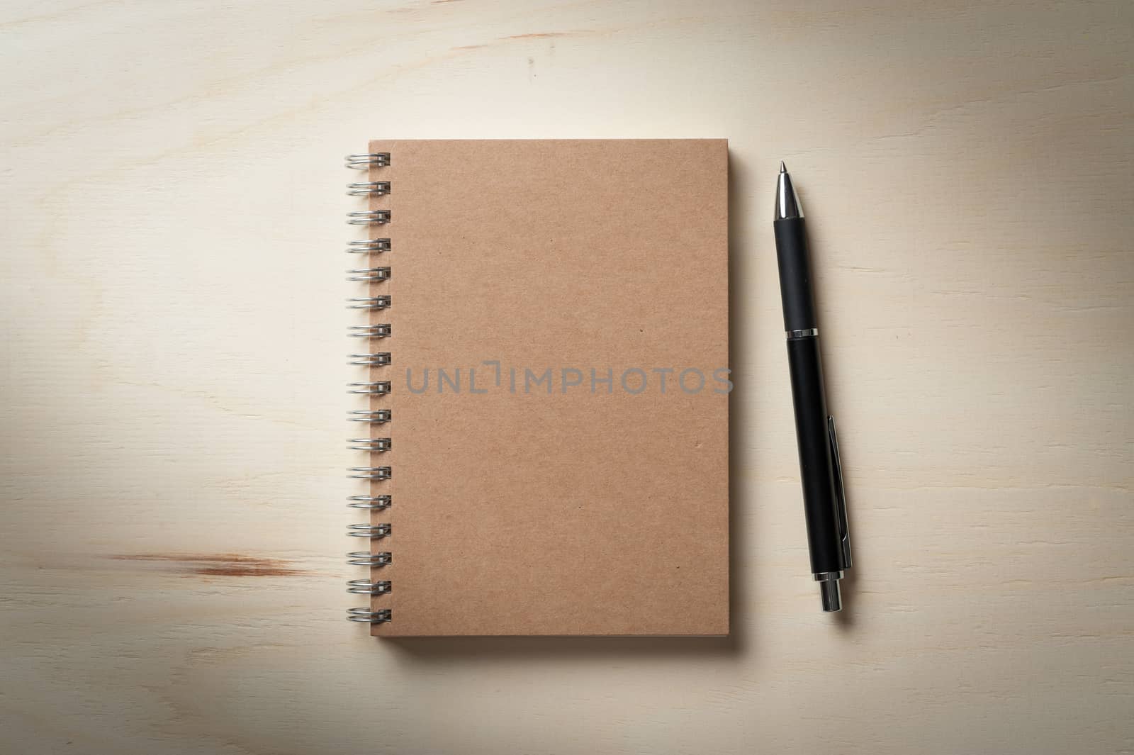 Closed notebook with blank area on front cover on wood table with low key scene