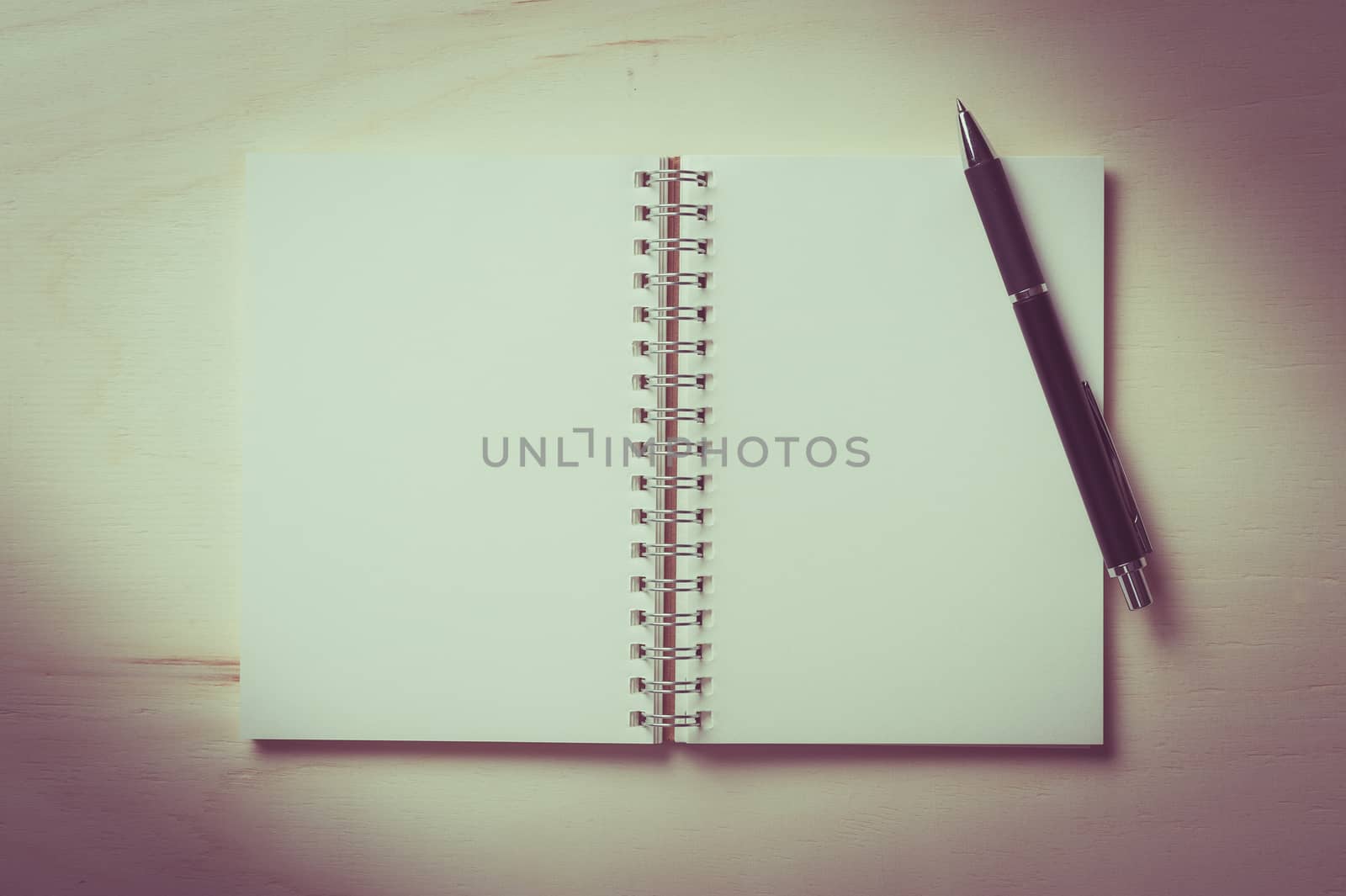 Opened notebook with blank area for text or message and pen on wood table with vintage filter effect