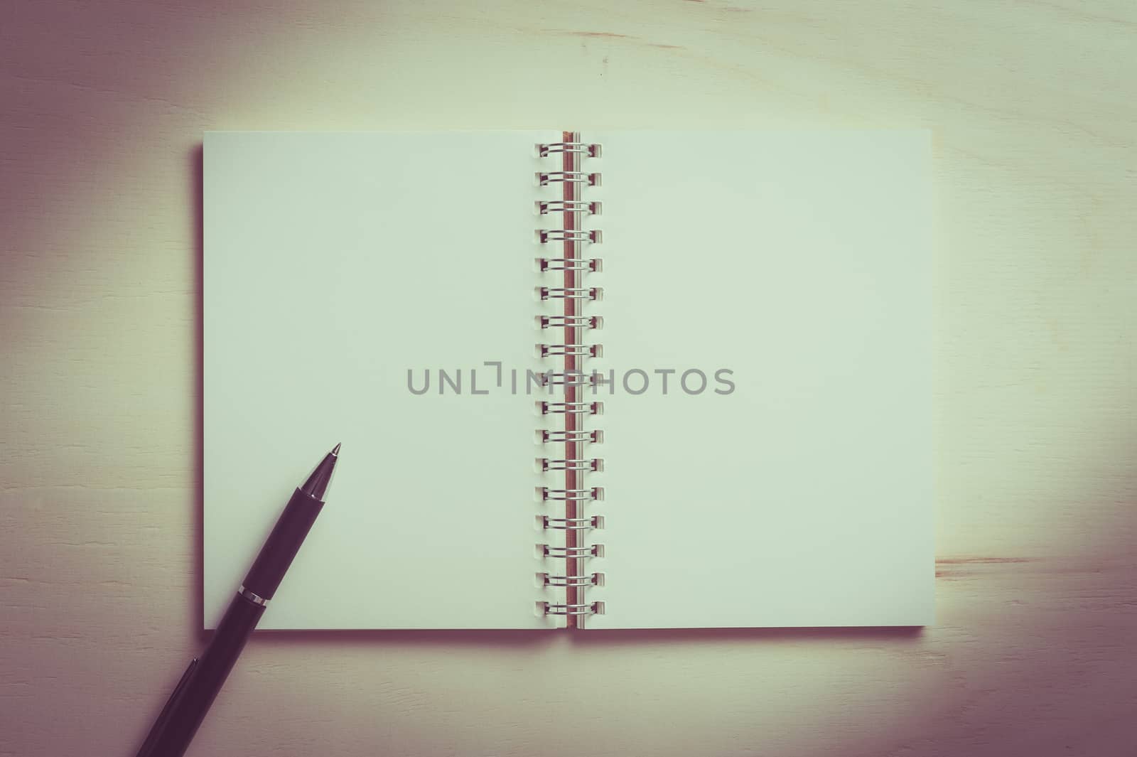 Opened notebook with blank area for text or message and pen on wood table with vintage filter effect