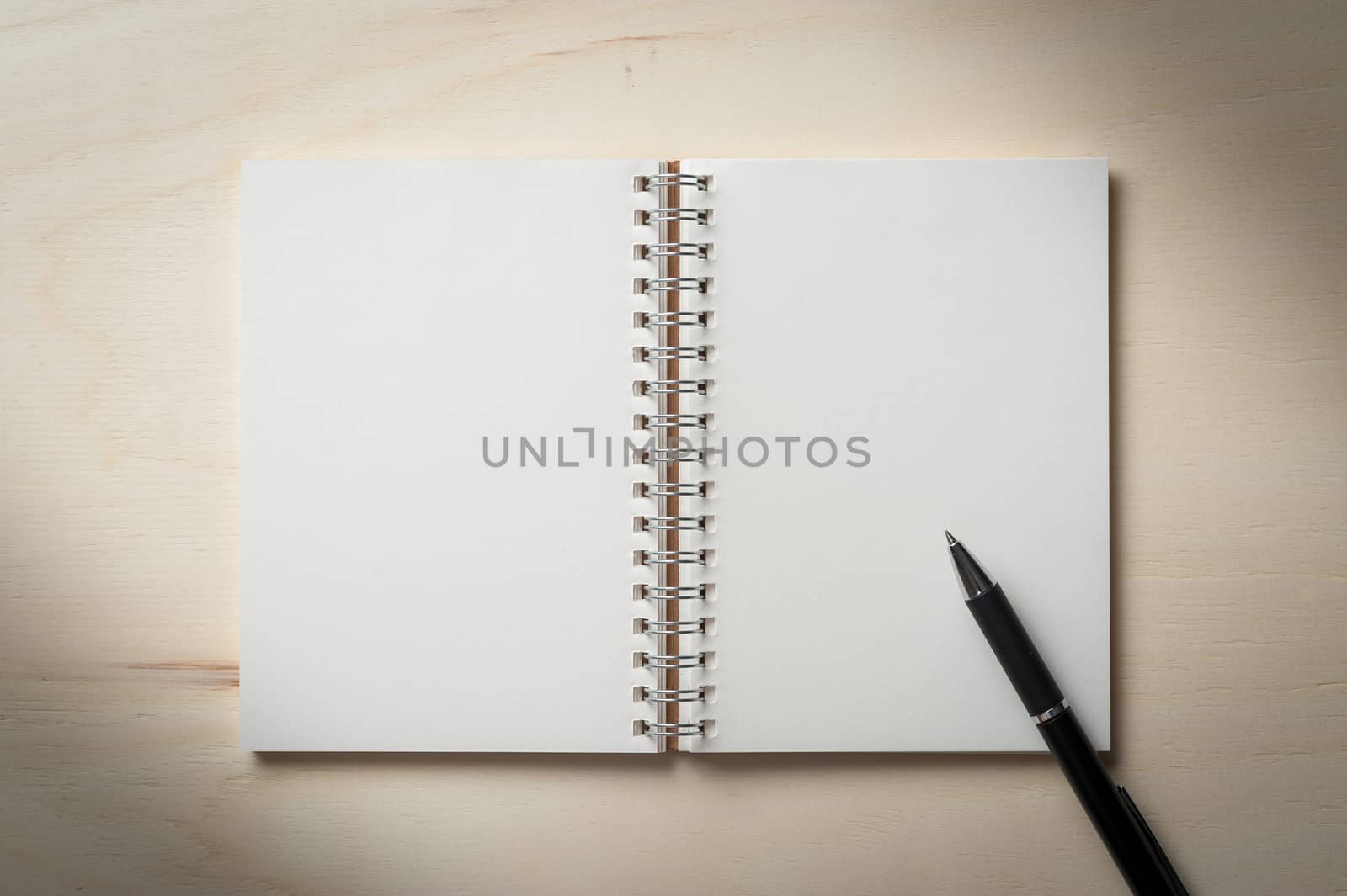 Opened notebook with blank area for text or message and pen on wood table with low key scene