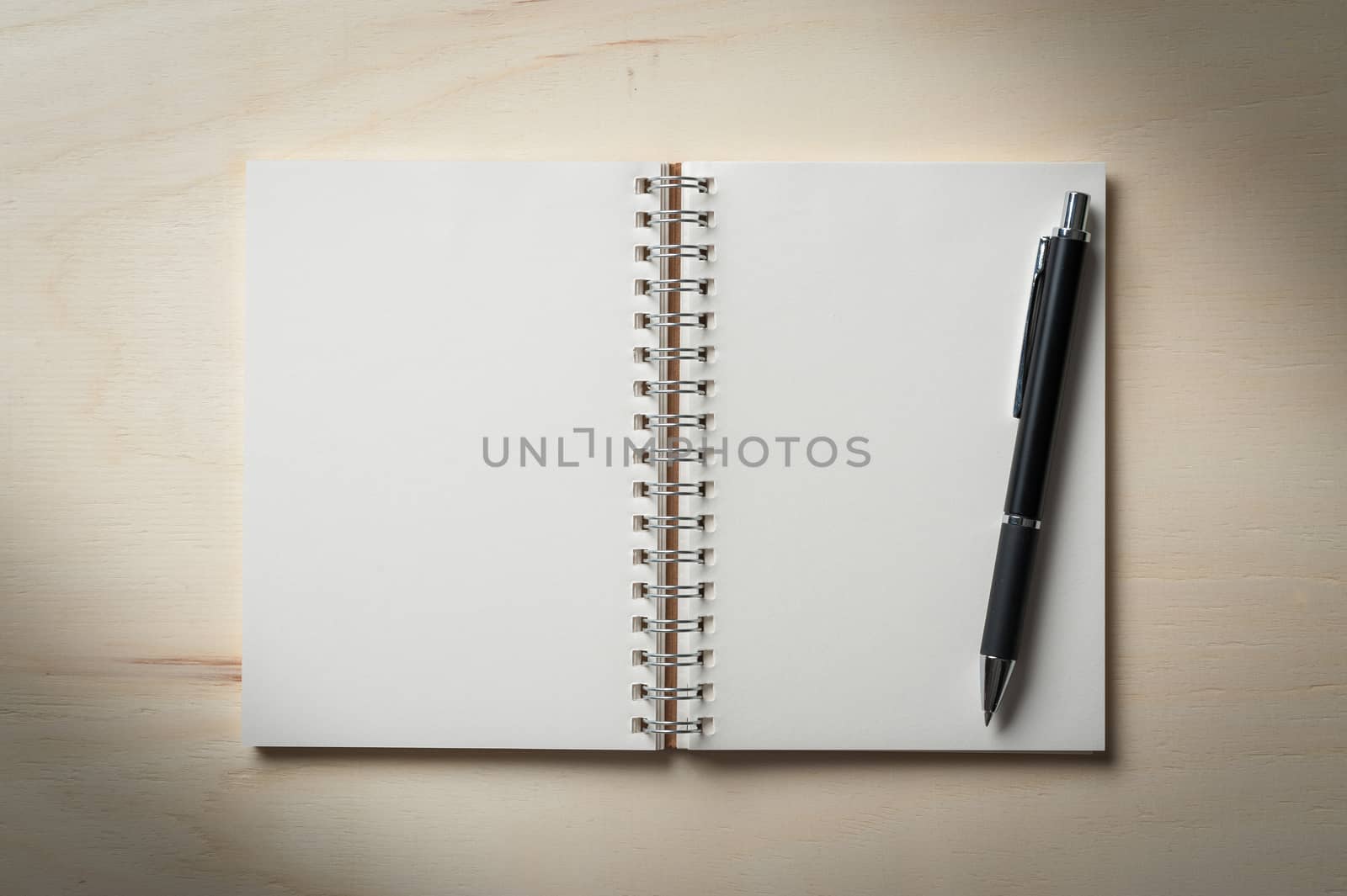 Opened notebook with blank area for text or message and pen on wood table with low key scene