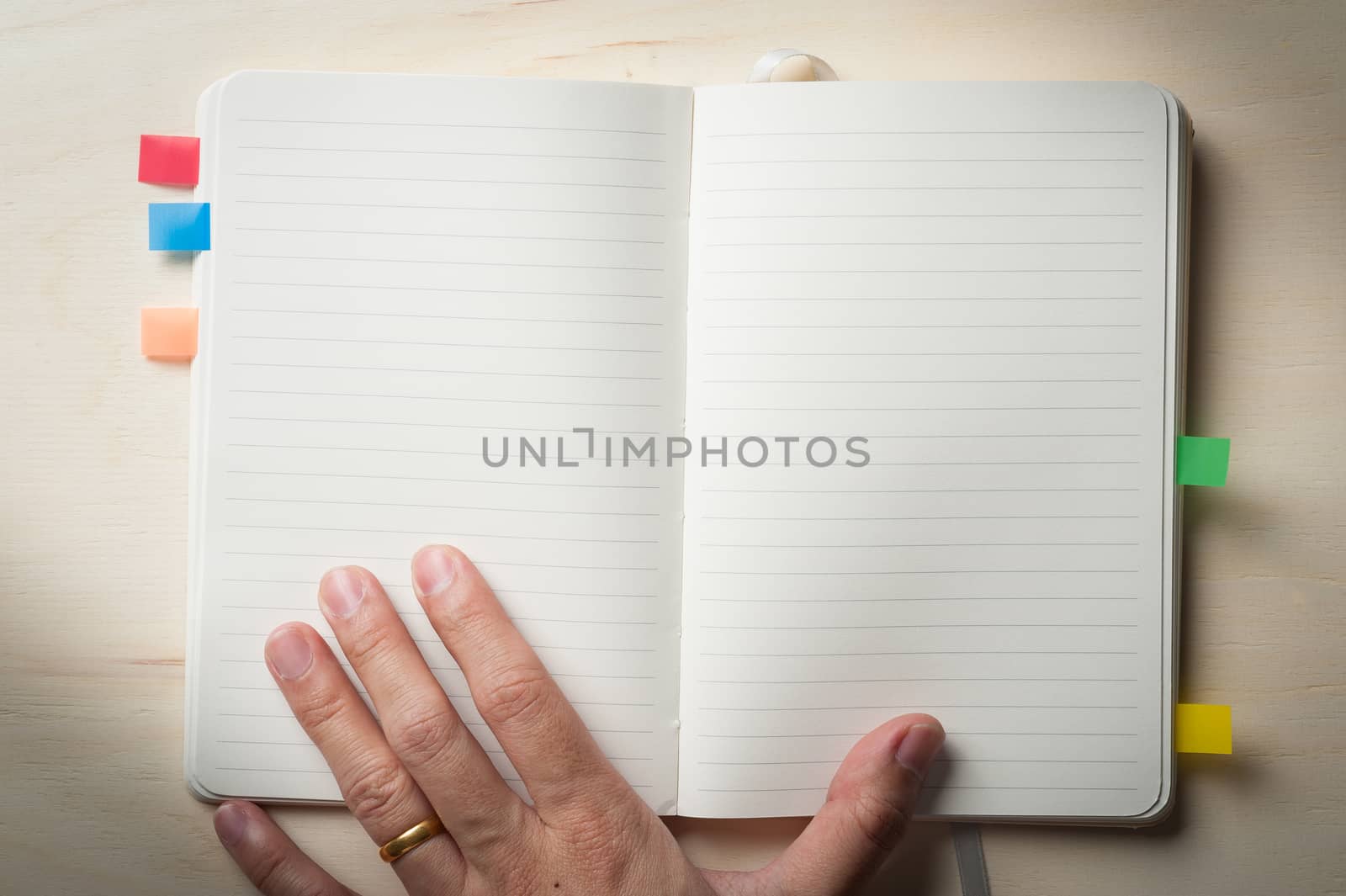 Male left hand touch at opened notebook with blank area for text or message on wood table in morning time with low key scene