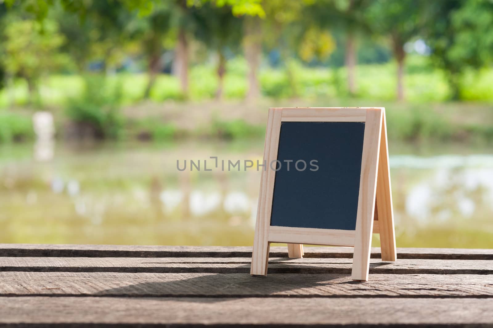 Small A-frame blackboard with blank area for text or message on rustic wood table in morning time