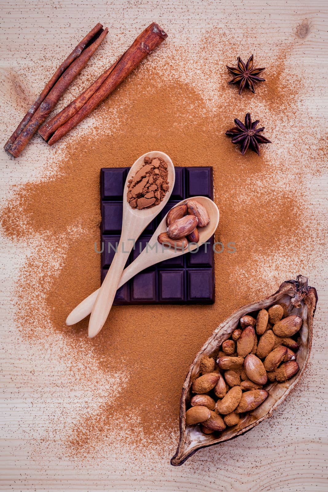 Brown chocolate powder in spoon , Roasted cocoa beans in the dry cocoa pod fruit and dark chocolate setup on wooden background.