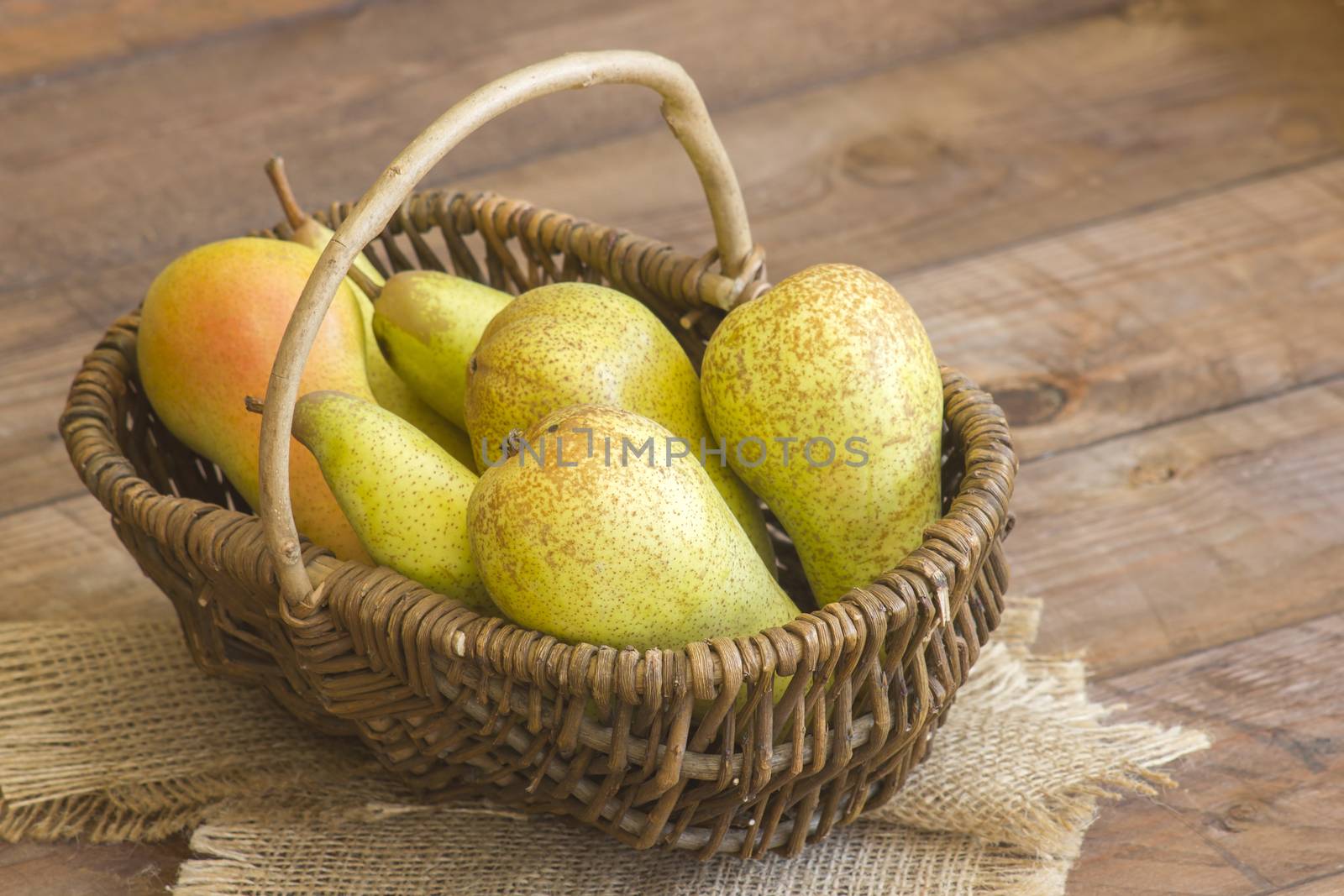 Juicy fresh pears in a basket on dark wooden background