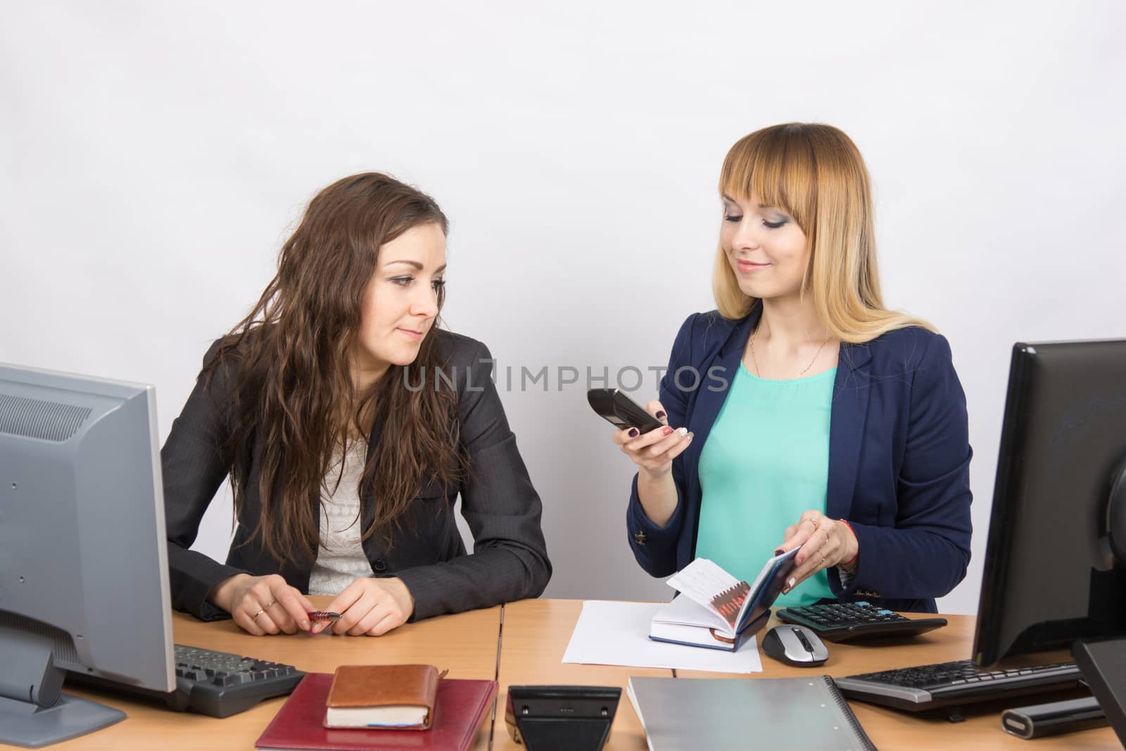 The girl in the office watching a colleague on the phone dials the number
