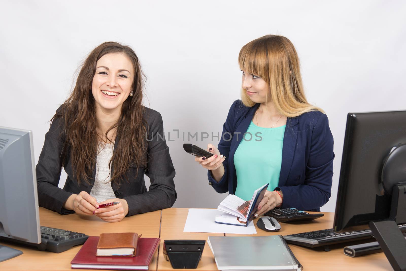 Office colleagues girl sitting at a desk and talking happily
